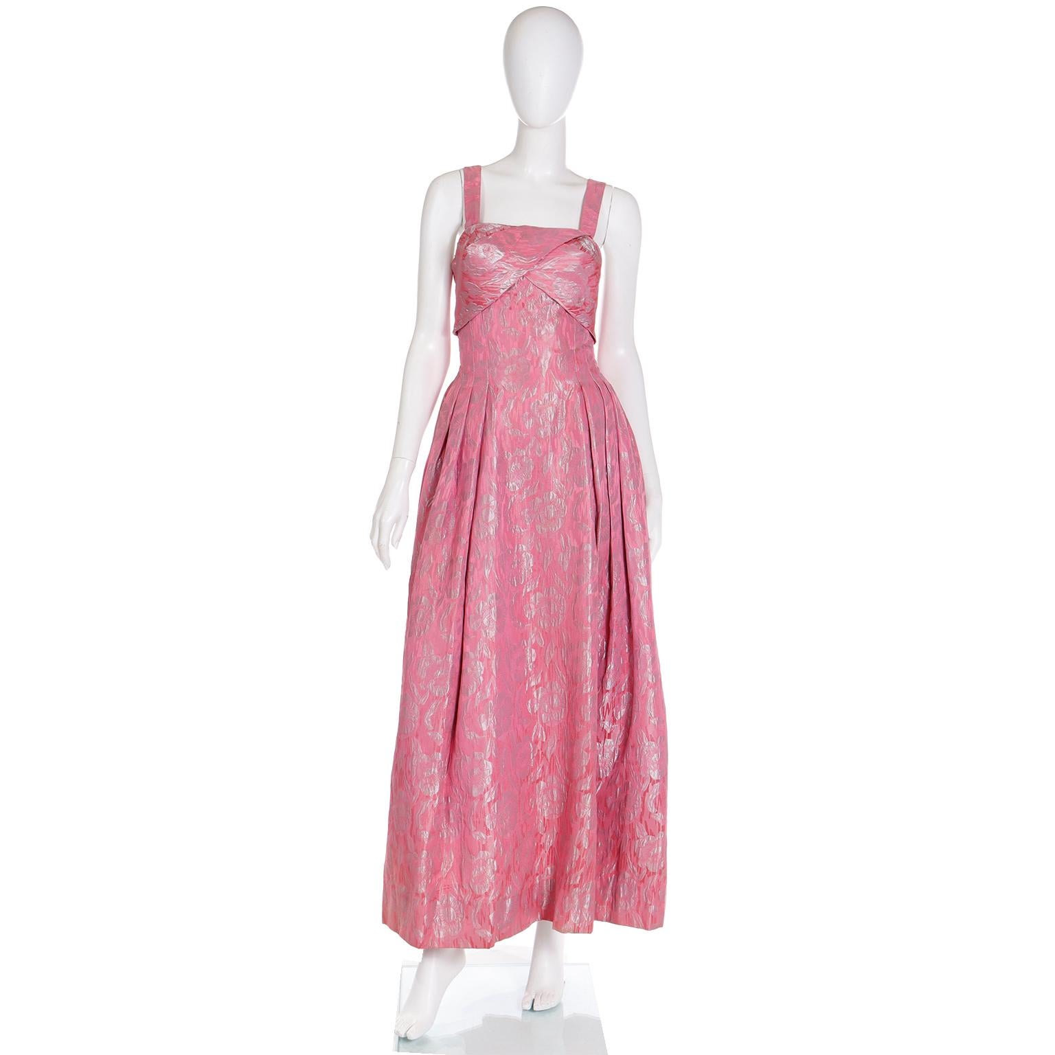 This lovely 1950s floor length vintage dress is by Norman Young, a London designer who designed special occasion and evening wear for high end boutiques.. The gorgeous jacquard print has a shimmering silver hue over the pink.  We especially love the