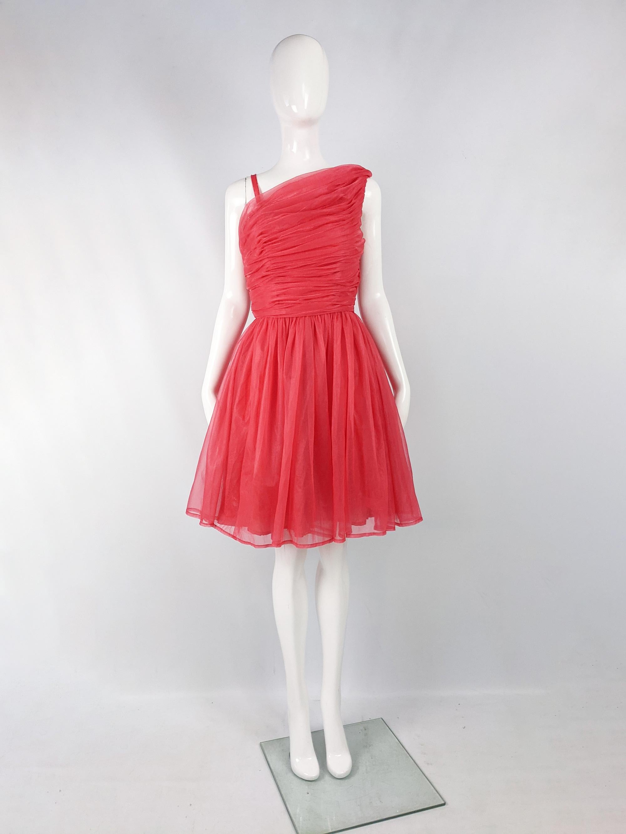 A fabulous vintage party dress from the early 60s by quality British designer, Norman Young. In a coral pink chiffon / organza fabric with ruching on the bodice, a full skirt and an asymmetric design on top. Perfect for an evening event. 

Size: