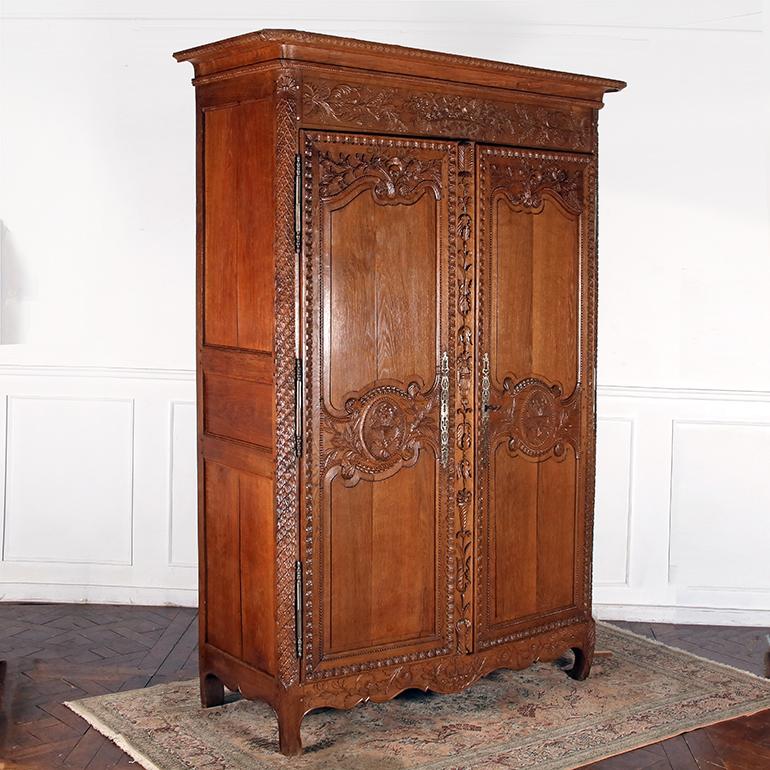 A late 18th Century, Normandy Style armoire in solid oak with an incredible amount of exceptionally fine carvings from it’s Cornice down to the skirt. The frieze features a carving of a floral cornucopia flanked by foliage, and at the centre of each