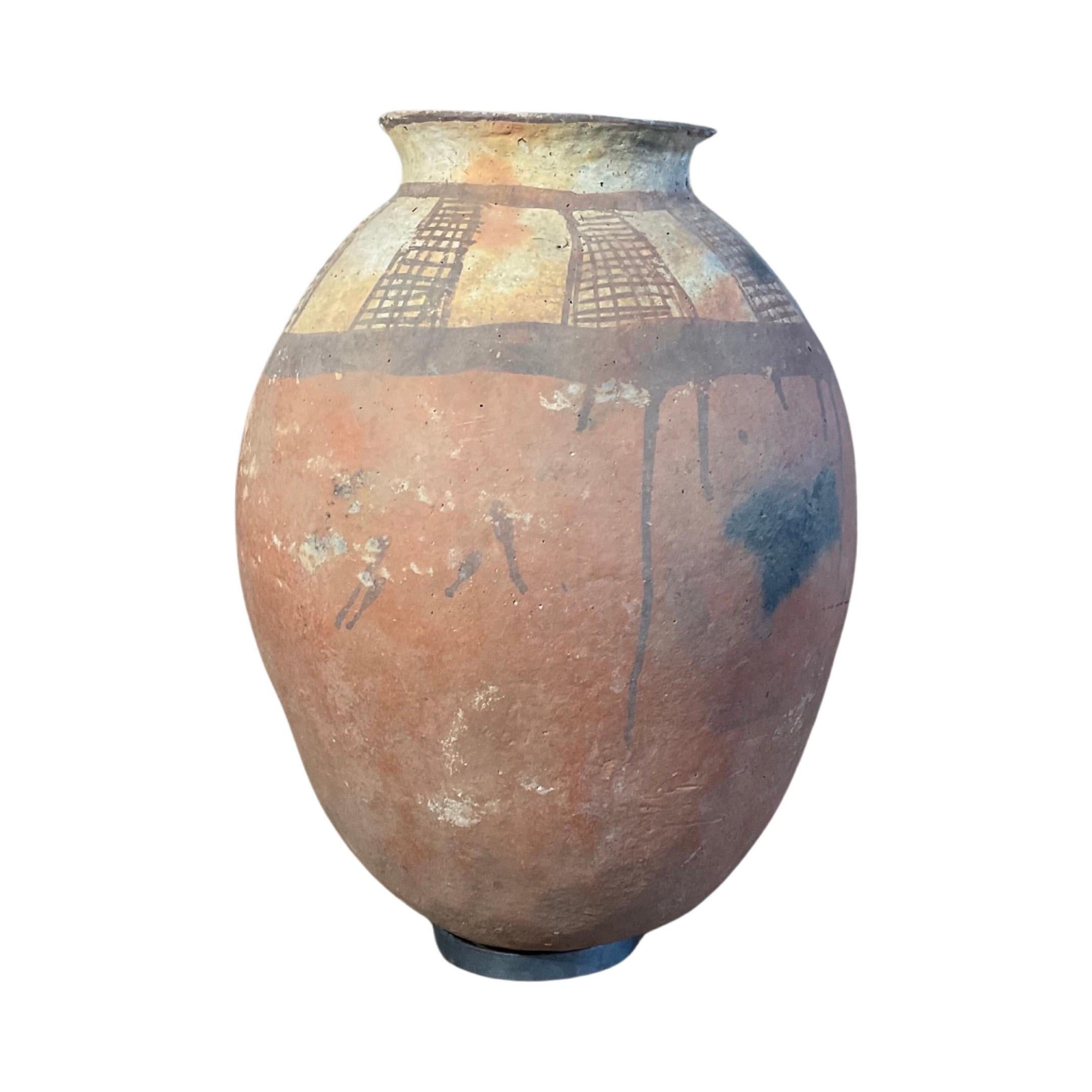 Ce récipient en terre cuite d'Afrique du Nord, unique en son genre, est une pièce ancienne à laquelle est attaché un support de base rond pour un maintien sûr. Ses motifs de style africain délavés et décolorés en feront à coup sûr un ajout unique et