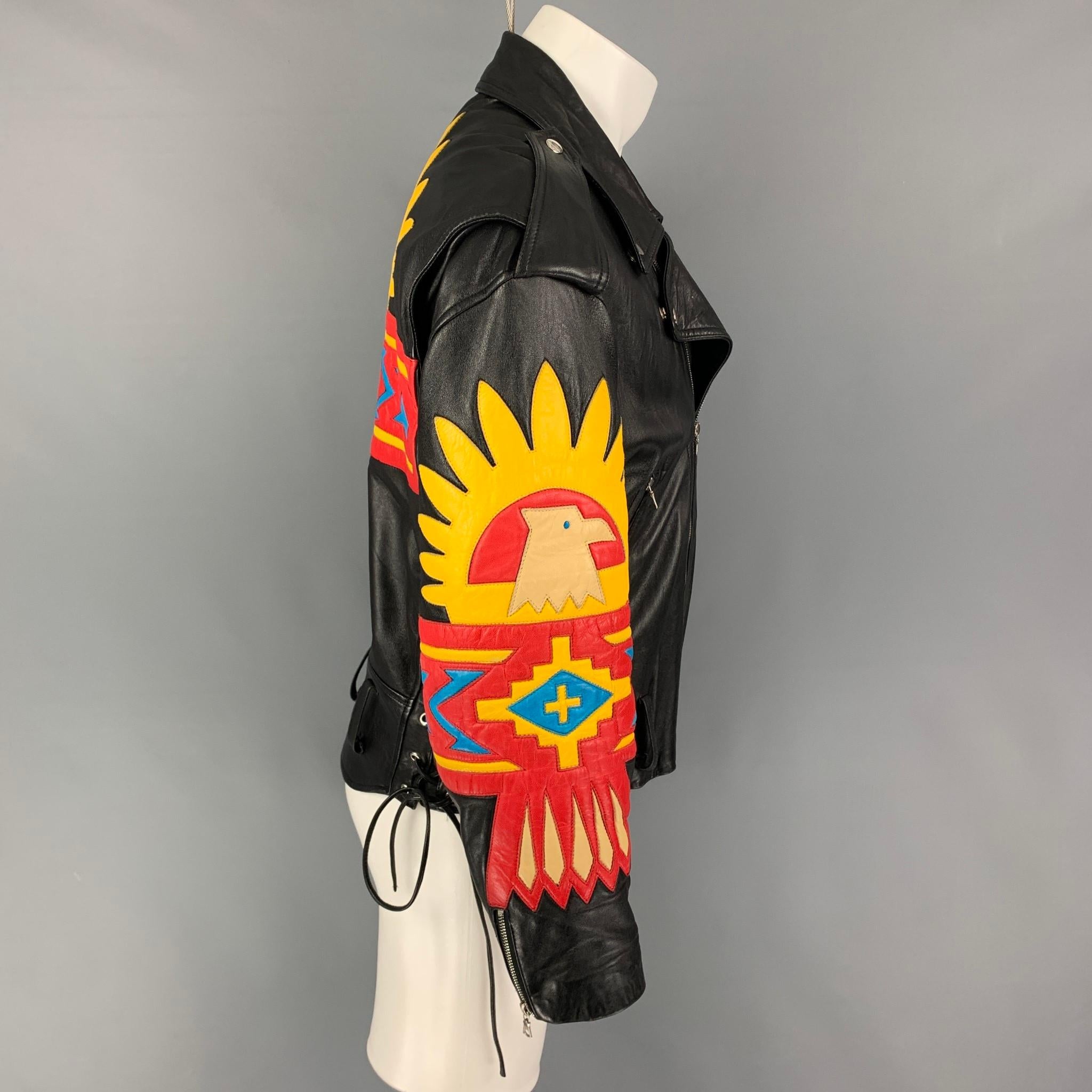 NORTH BEACH LEATHER x MICHAEL HOBAN jacket comes in a black leather with multi-color applique designs featuring a biker style, silver tone hardware, epaulettes, zipper pockets, side self-toe straps, and a zip up closure. 

Very Good Pre-Owned