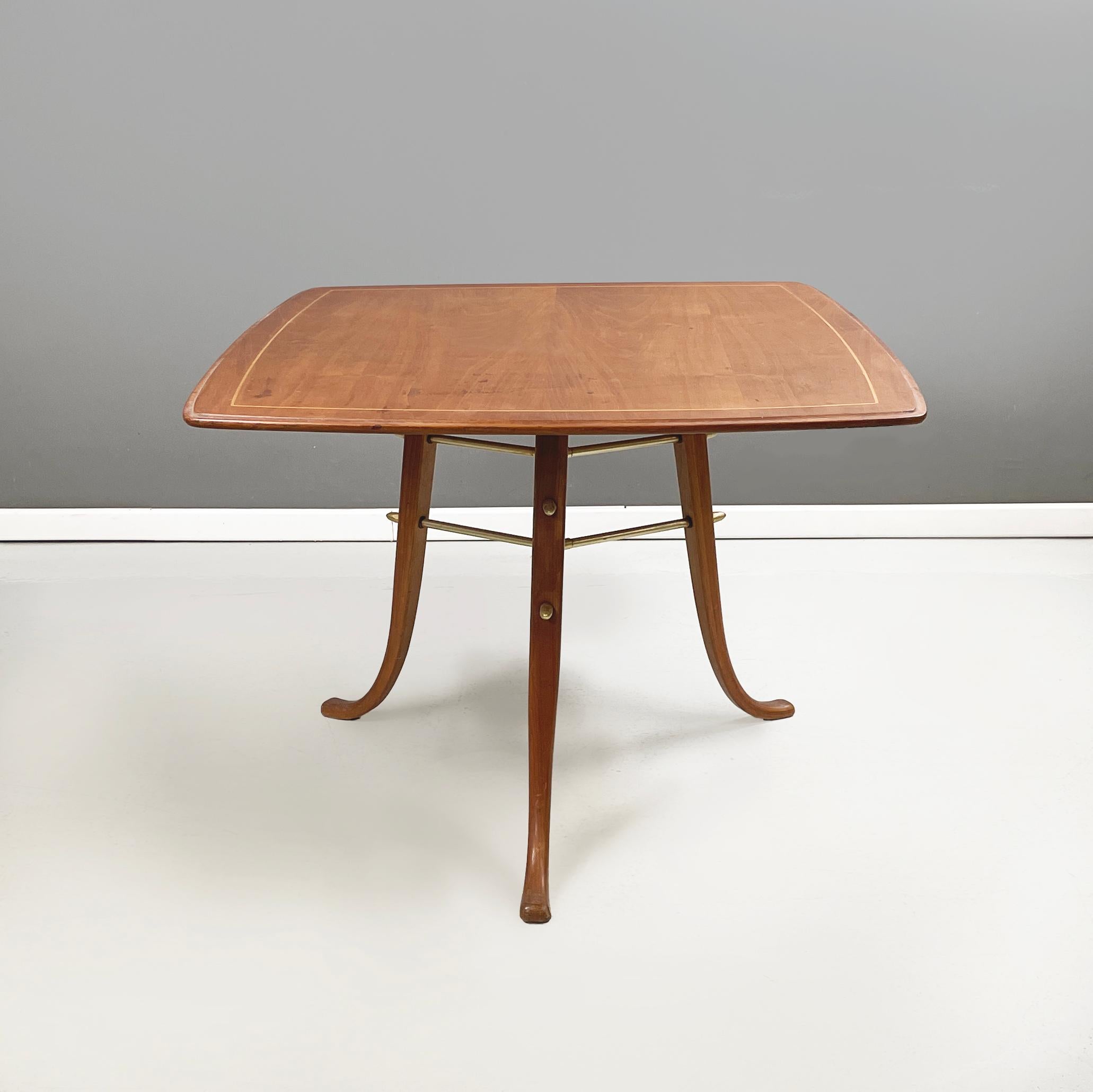 North European mid-century modern Squared coffee table in wood and brass, 1960s
Coffee table with rectangular top with rounded wooden corners, with light wood detail on the profile. The three round wooden legs are joined in the center by a brass