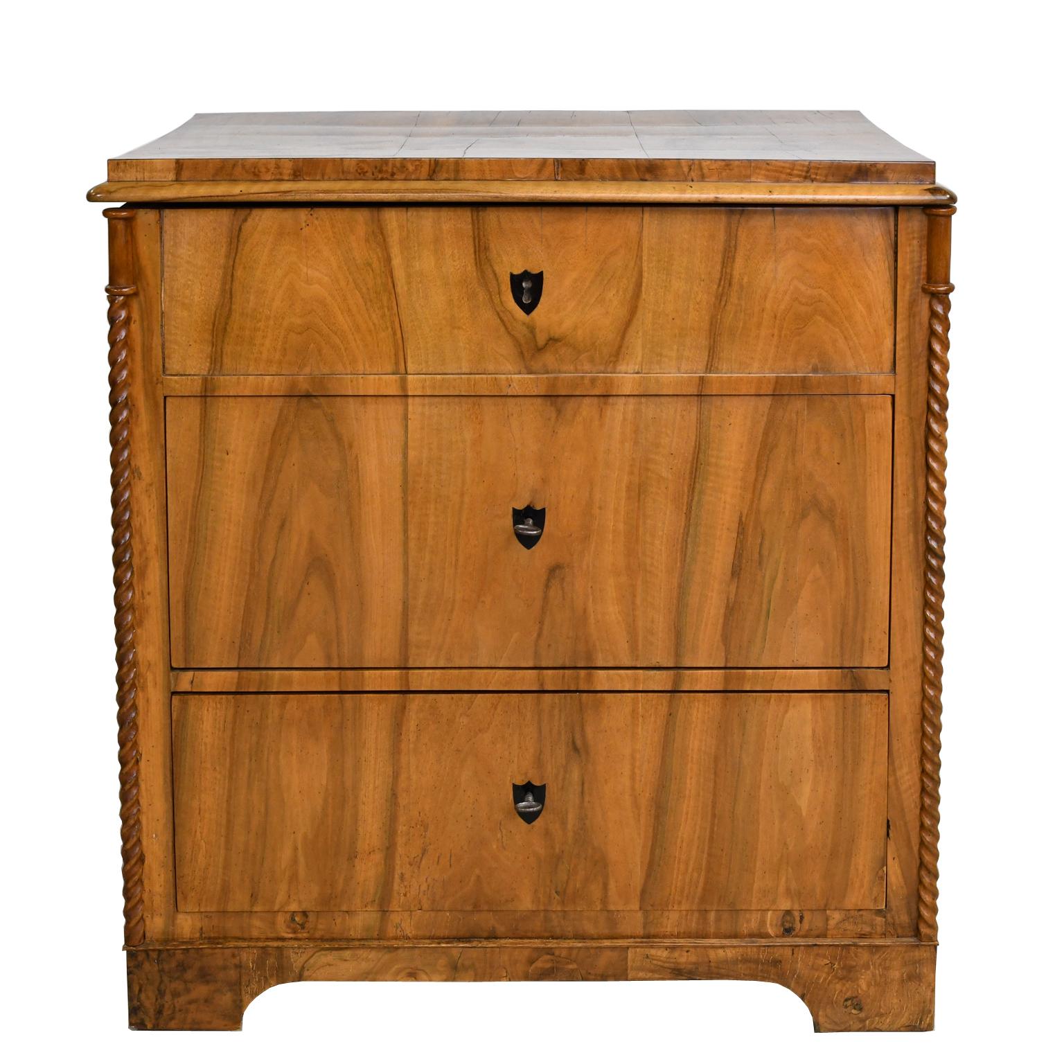 A small period North German Biedermeier chest in beautiful figured walnut with two drawers and a hinged lift-top. Chest has carved rope-turnings on the front corners, inlaid ebony key escutcheons, and rests on bracket feet. Northern Germany, circa