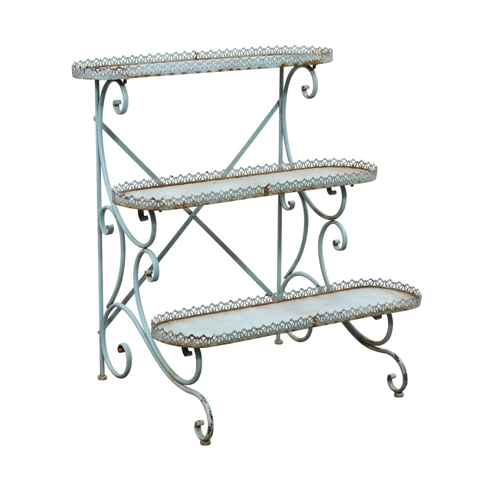 A French blue painted iron three-tiered plant stand from the 20th century with pierced gallery and scrolling legs. This French blue painted iron plant stand, hailing from the 20th century, is a delightful addition to any garden or home space.