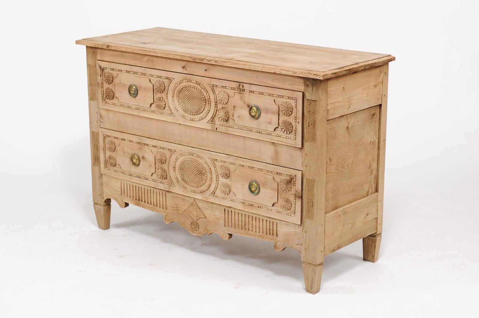 A northern French Louis XVI style stripped oak commode from the early 20th century, with two drawers, beaded motifs and carved medallions. We love the Louis XVI classical lines, the decorative flourishes and the contrast with the rustic nature and