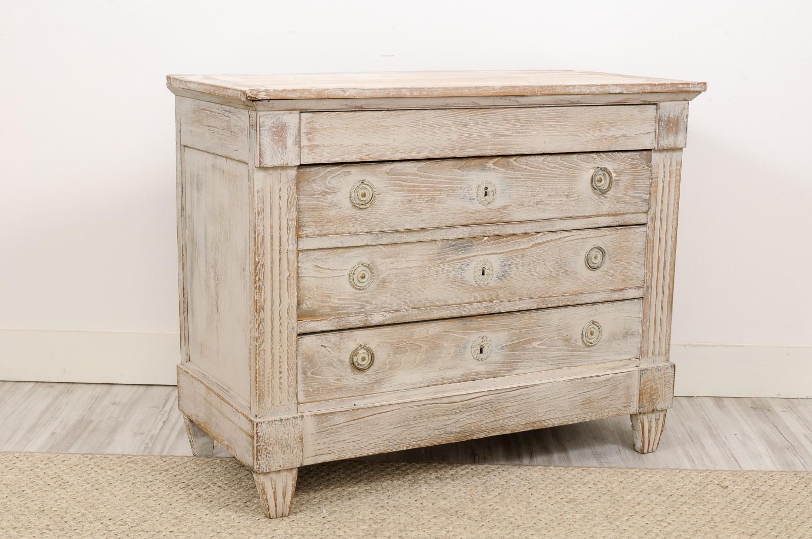 A northern French Louis XVI style blanched commode from the late 19th century with four drawers, fluted side posts and tapered feet. We love the Louis XVI details, like the fluted feet, the pretty patina and the secret drawer on top. With its clean