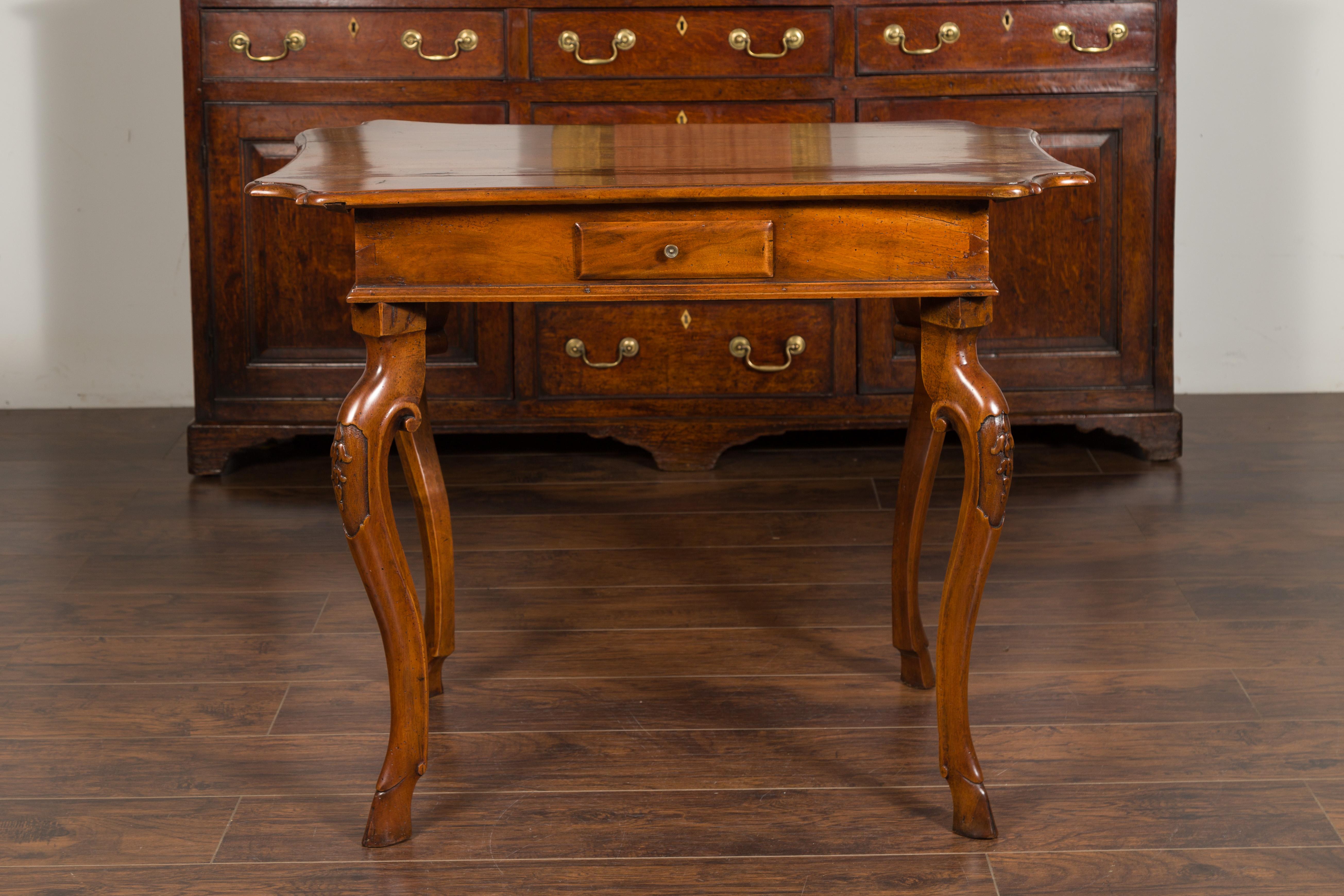 A Northern Italian Régence period walnut side table from the early 18th century, with four drawers, cabriole legs, hoofed feet and carved foliage. Created in Northern Italy during the first quarter of the 18th century, this walnut side table