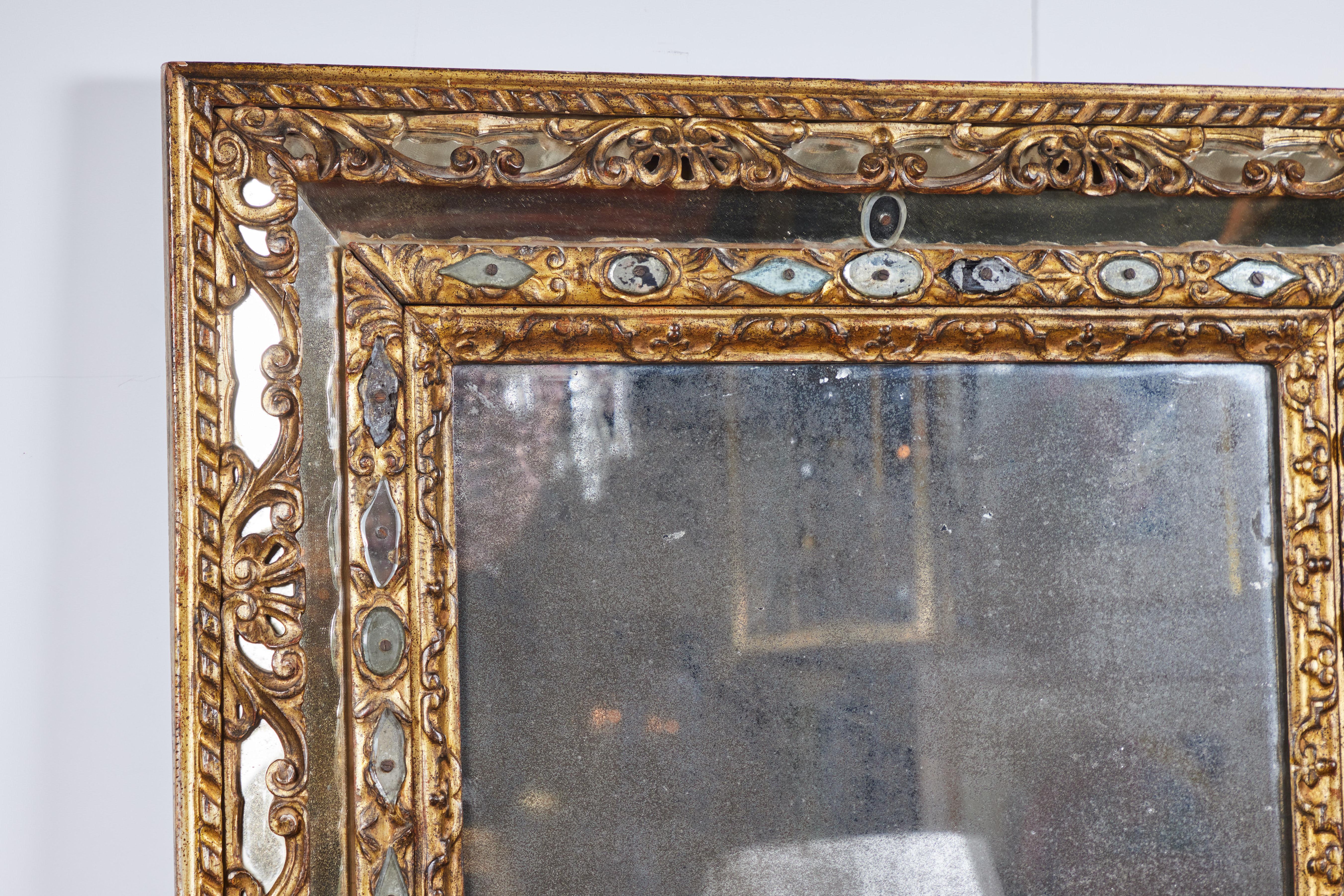Un élégant miroir en bois doré sculpté avec des accents de miroir coupé.  Verre miroir original en poussière de diamant avec des taches et des pertes.