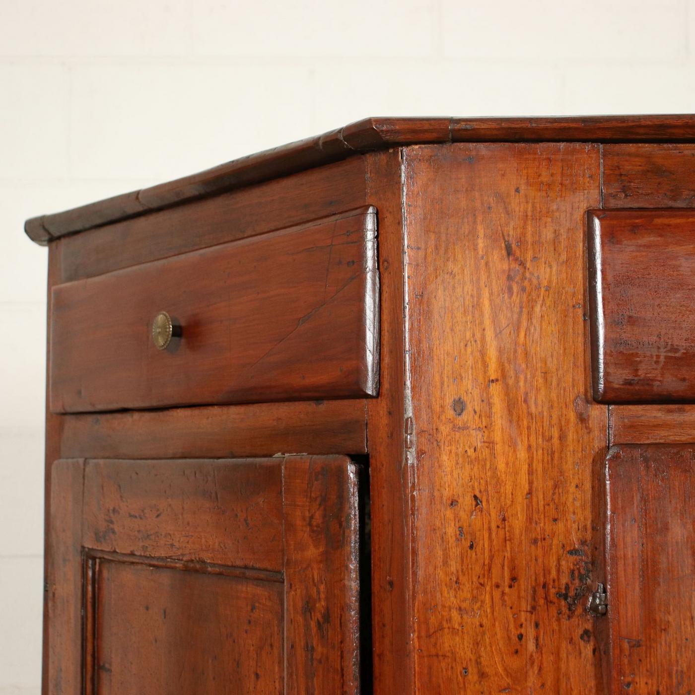 The rectangular top with canted angles, the conforming case fitted with four drawers above cupboards enclosed by recessed paneled doors, on bracket feet.