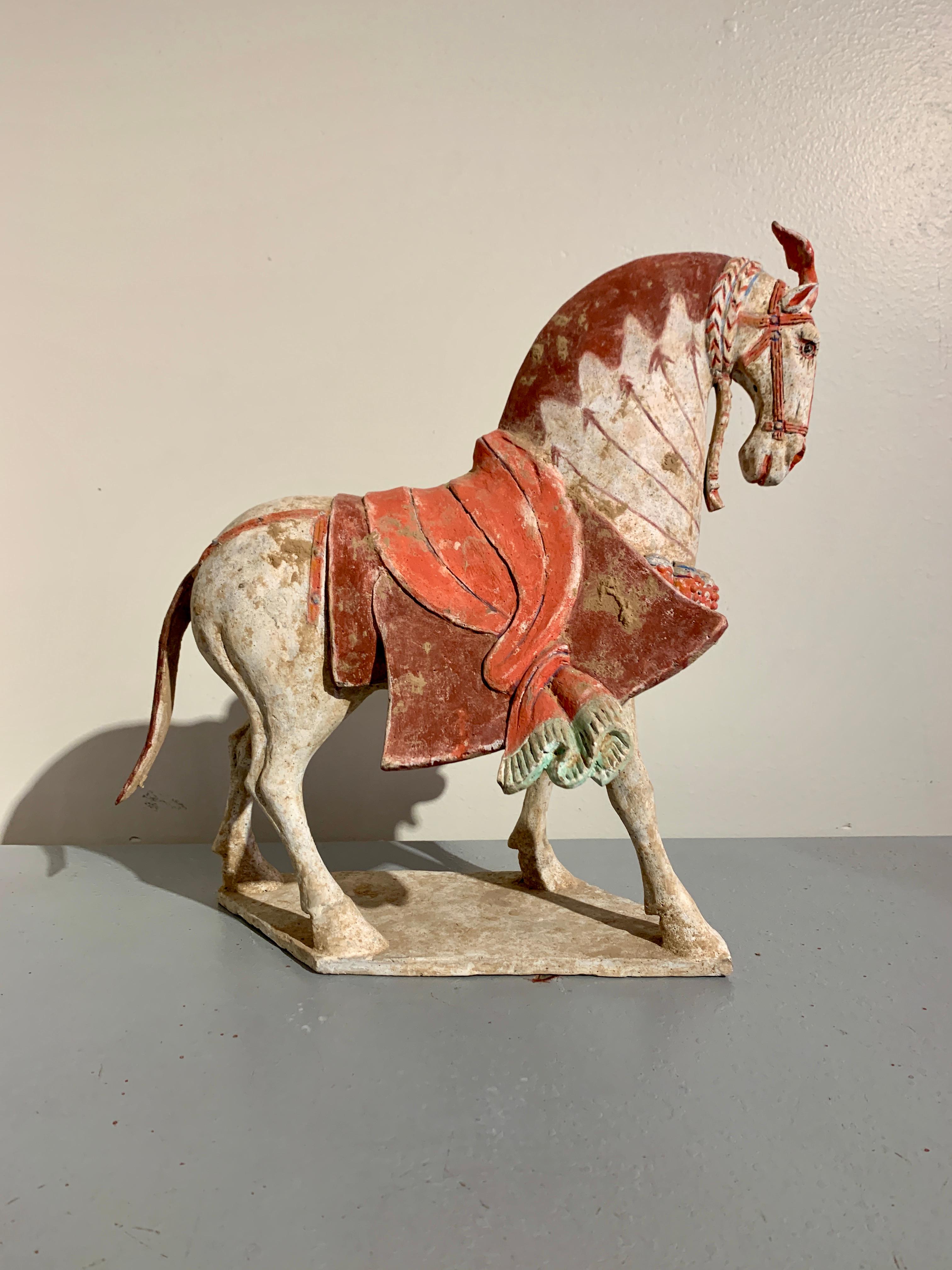 Un magnifique modèle de poterie peinte chinoise représentant un cheval caparaçonné marchant à grands pas, dynastie Qi du Nord (550 à 577 ADS), Chine, TL testé par Oxford Laboratories. 

Le noble cheval est représenté à mi-course sur une base