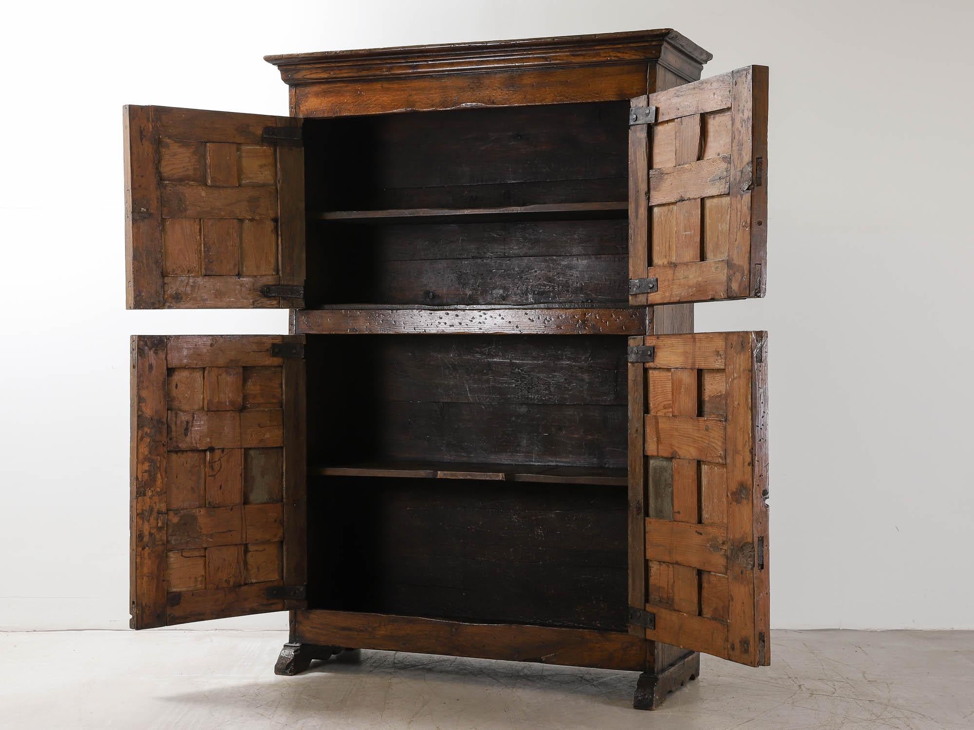 This substantial 19th Century Northern Spanish cabinet in oak and pine was most likely originally used as kitchen storage - with four geometrically carved panel doors, original iron hinges, internal shelves, standing on a plinth base. The piece is