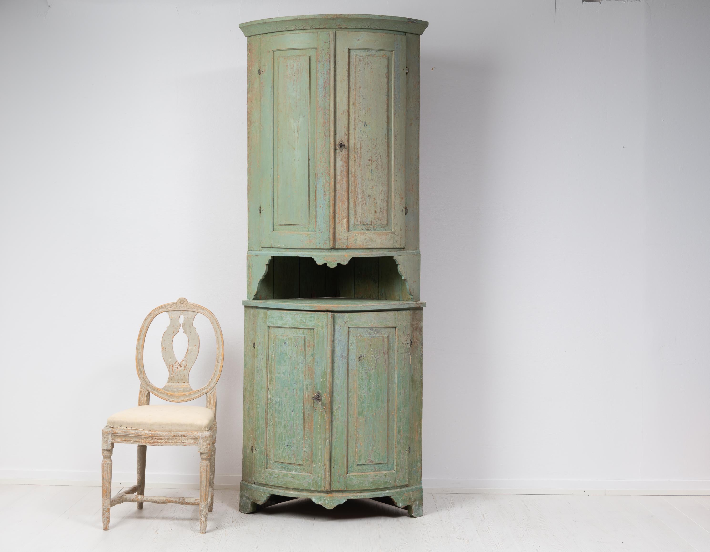 Swedish country corner cabinet from the late 1700s. The corner cabinet has a straight classic shape in gustavian style. Made in northern Sweden in two parts. The cabinet has scraped to original paint and the upper cabinet has a spoon shelf at the