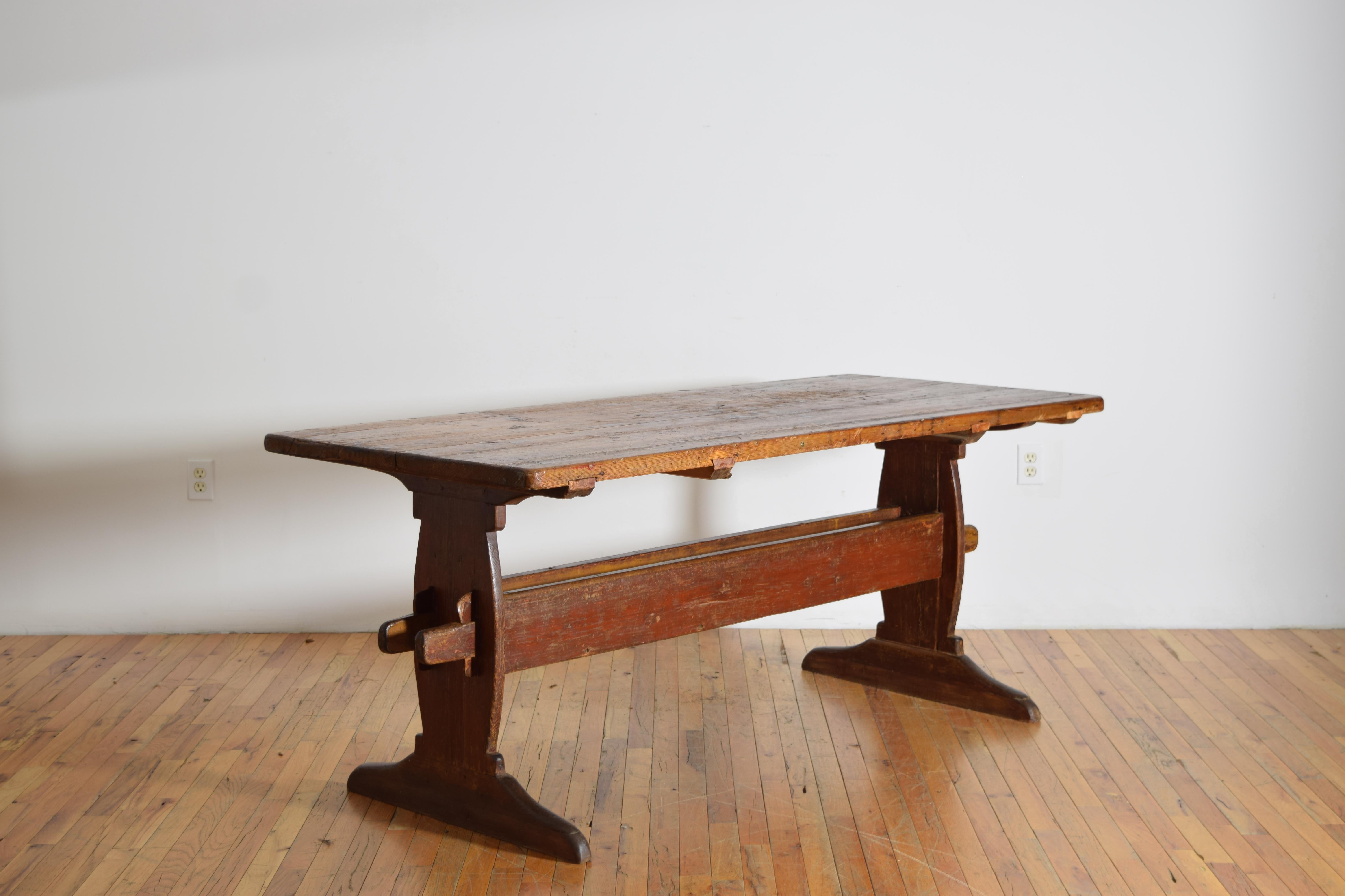 Le plateau rectangulaire épais avec des signes visibles de travail est surmonté d'un cadre à tréteaux avec un double châssis reliant les deux pieds, le châssis avec un puits de stockage à l'intérieur et maintenu en place par quatre grandes cales, le