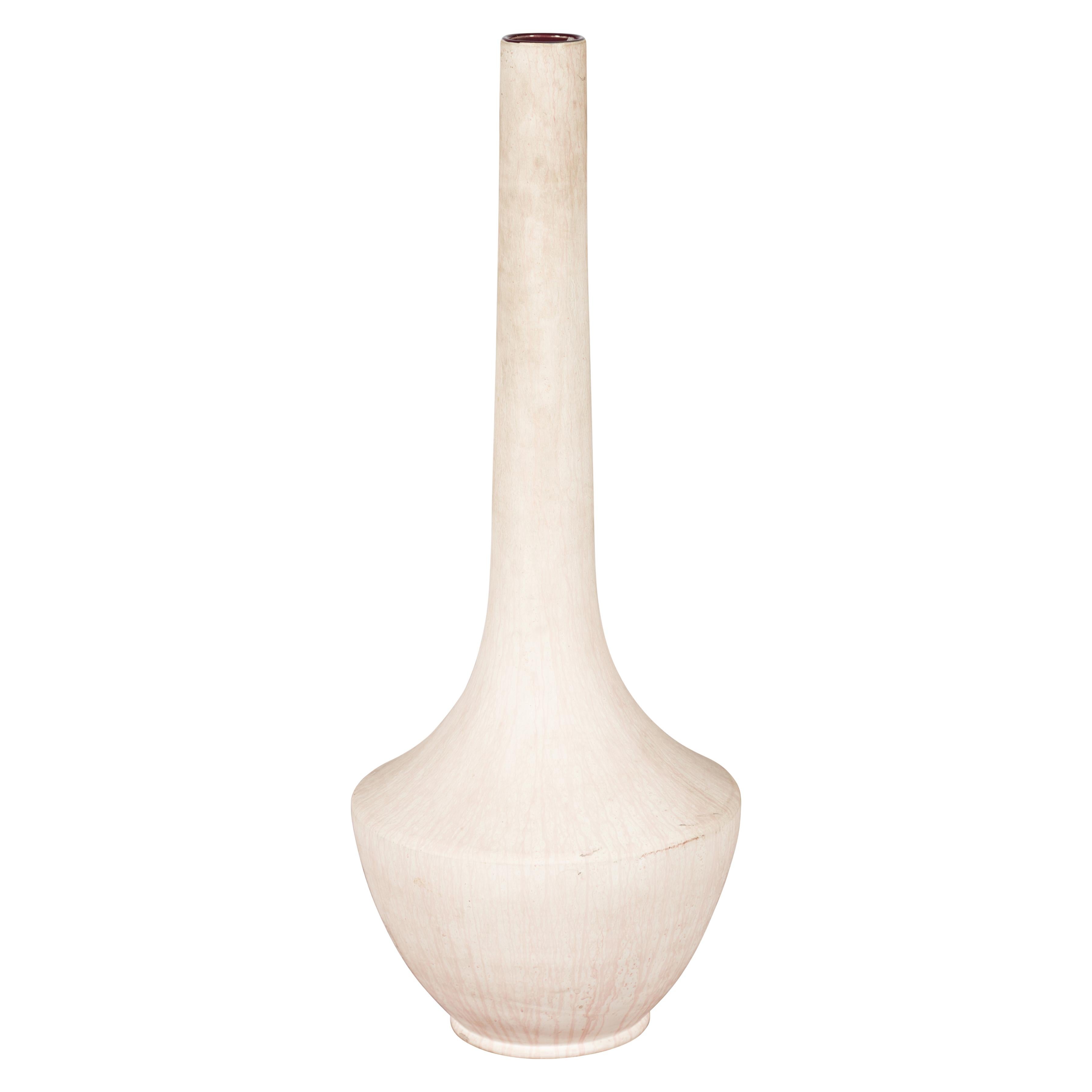Alto e scultoreo, questo vaso in ceramica lavorato a mano è una dichiarazione di tranquilla eleganza grazie al suo lungo collo e al suo profilo minimale. La finitura è un bianco morbido e gessoso con un sottile effetto craquelure che aggiunge