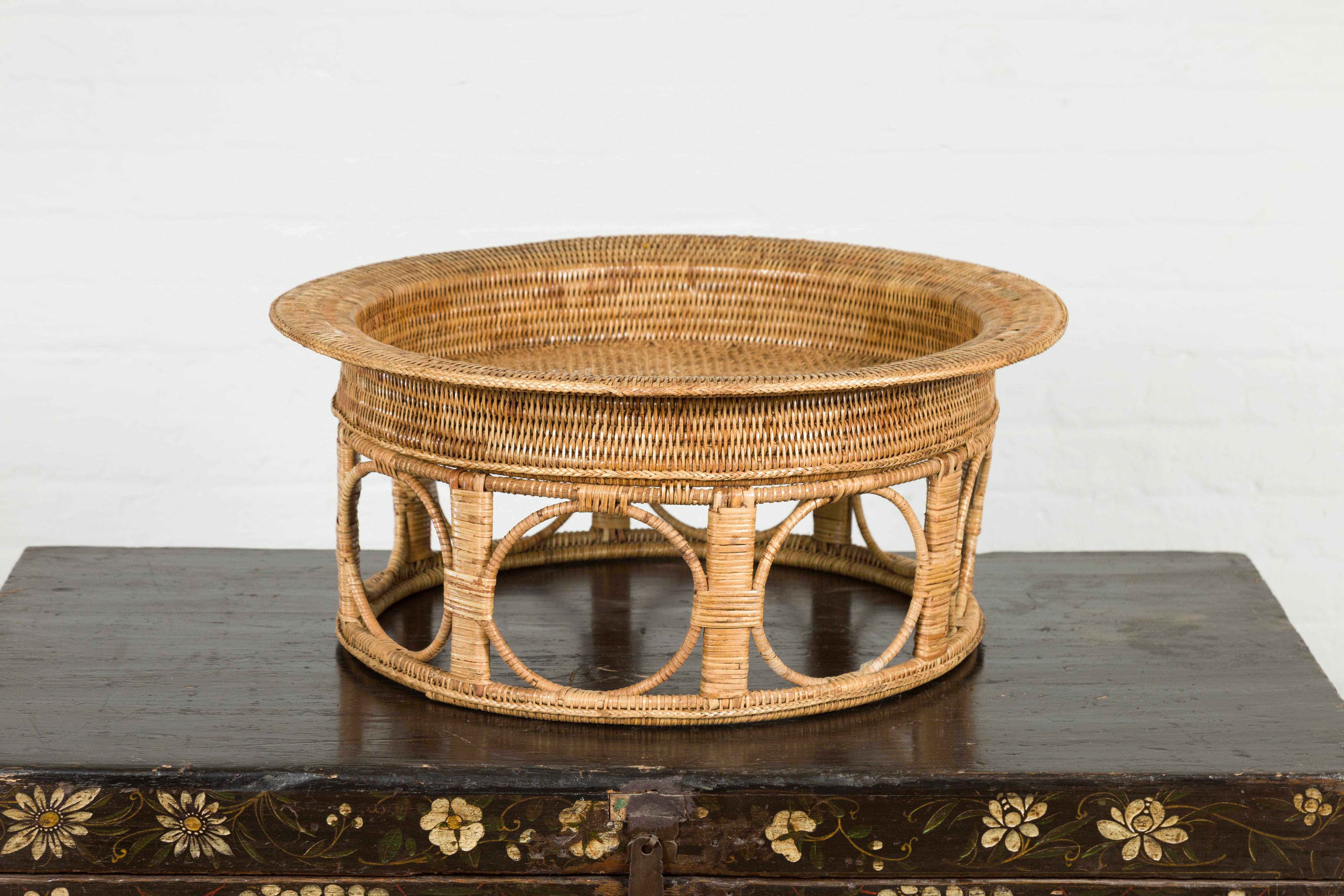 A vintage Thai Country style woven rattan Khantok pedestal fruit tray from the mid 20th century with circular shape and pierced ring motifs. Created in Northern Thailand by the Lanna people, this pedestal tray features a circular tray top sitting