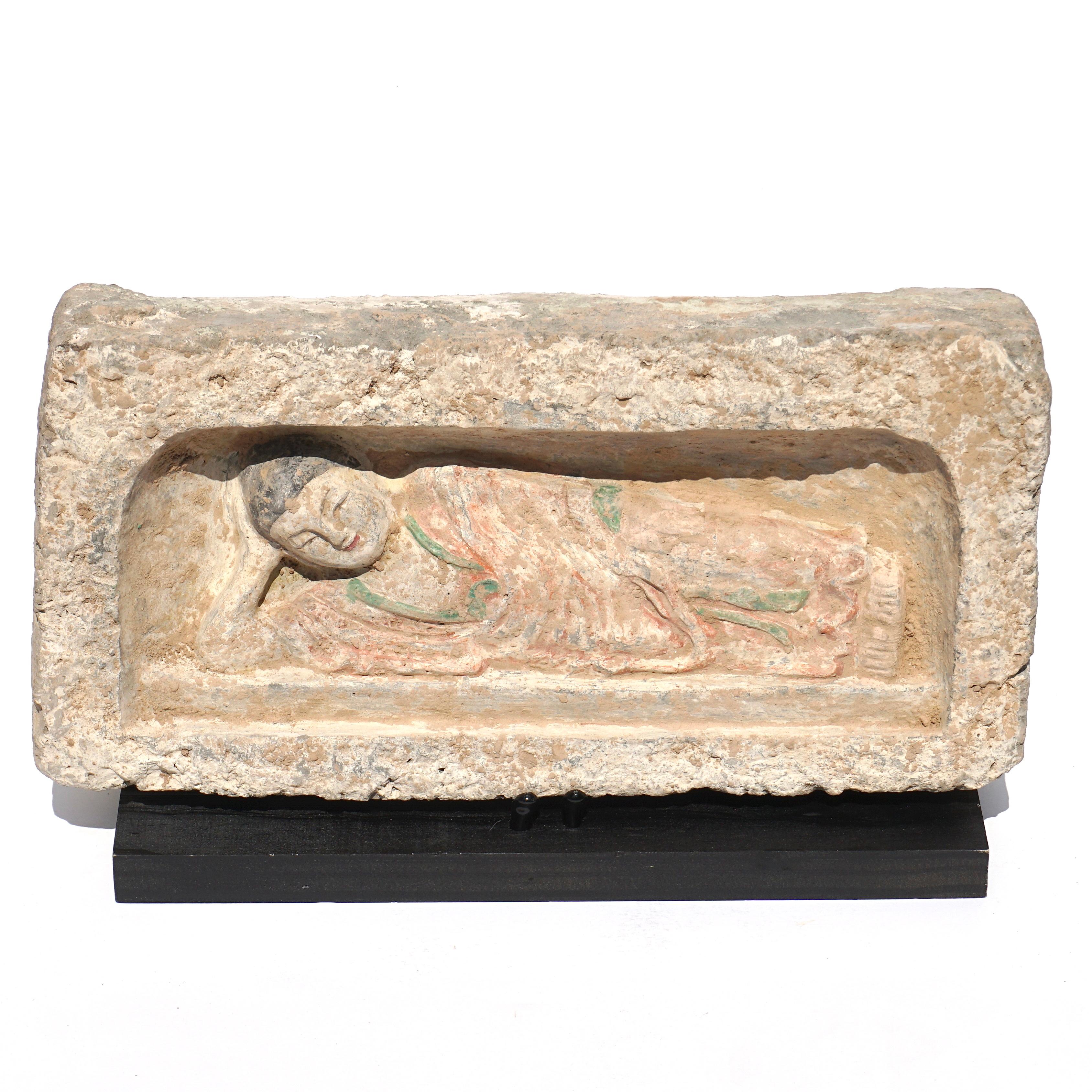 C. 386-534 AD. Northern Wei Dynasty. 

A interim Han-Tang Dynasty terrecotta painted brick featuring a reclining Buddha figure placed within a rectangular recess. Buddha, who supports his head with one arm, while the other is placed on his side,