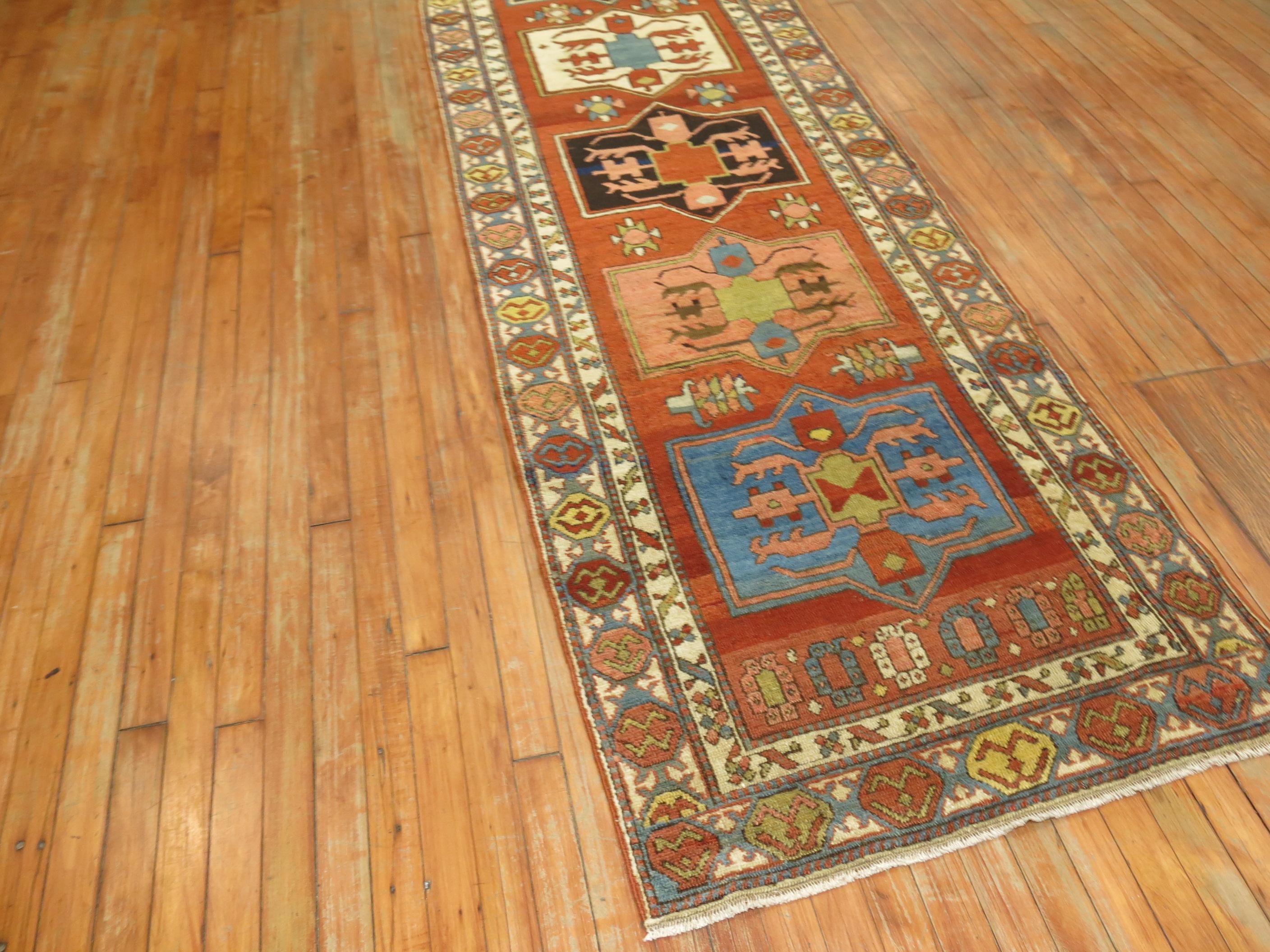 A high quality early 20th century northwest Persian runner. A brick field with open medallions in an array of earthy colors.