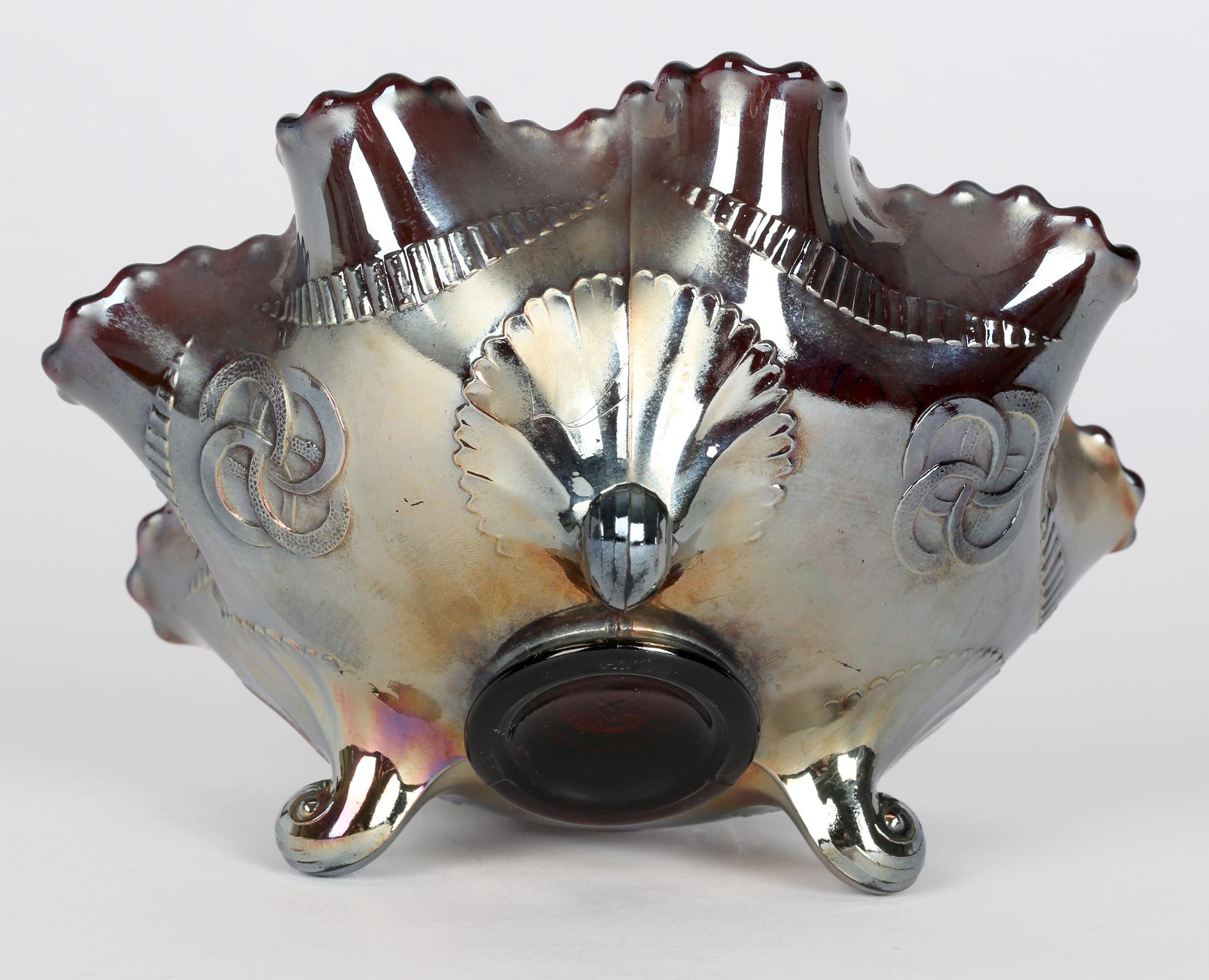A stunning North American carnival amethyst glass bowl decorated in the Wishbone pattern by Northwood and dating from the early 20th century. The bowl stands raised on three scroll legs the rounded body with a pinched ruffled rim with the inner bowl