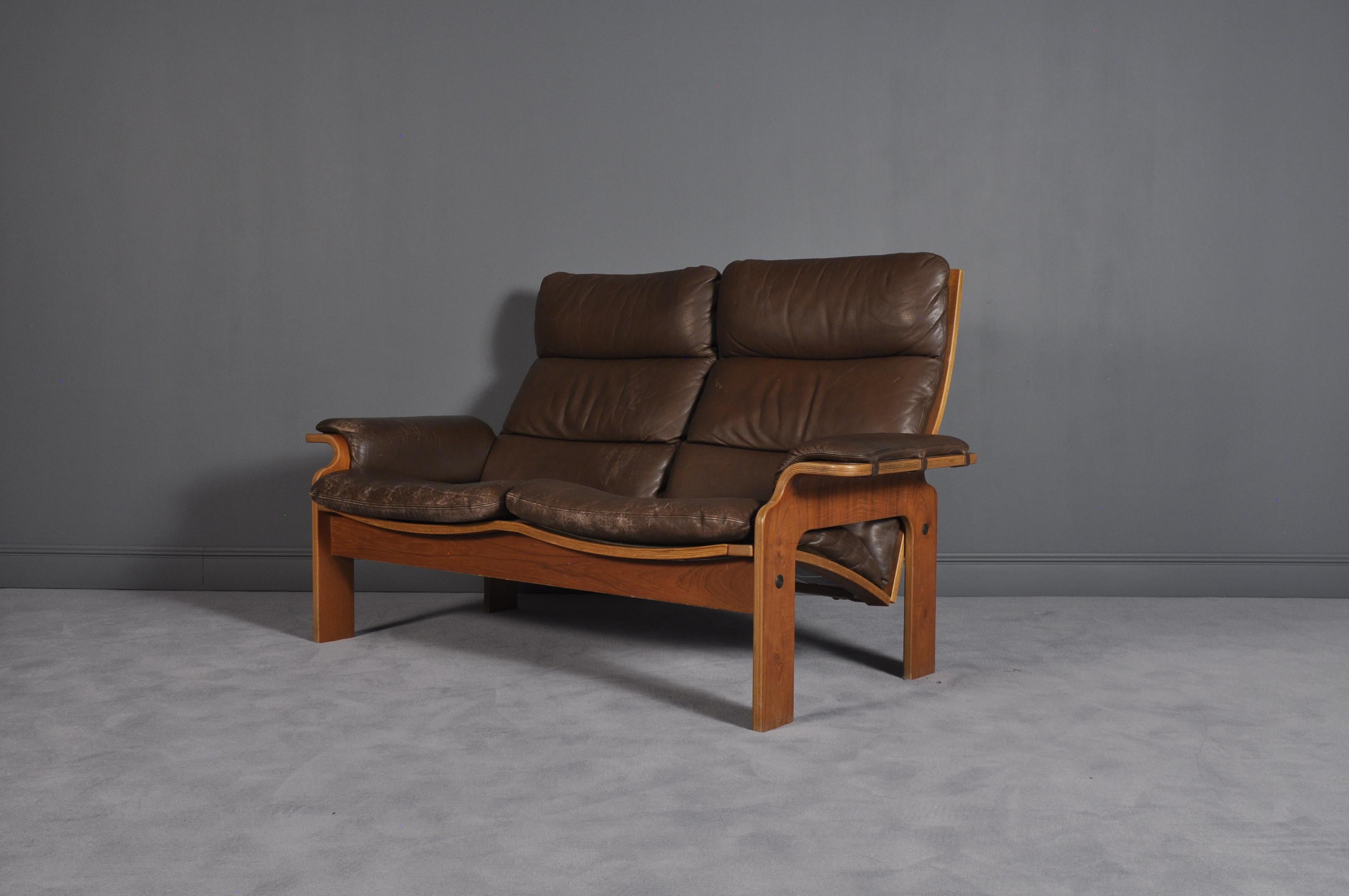 This two-seat brown leather sofa was made by a Norwegian furniture producer. It features an organic shape.