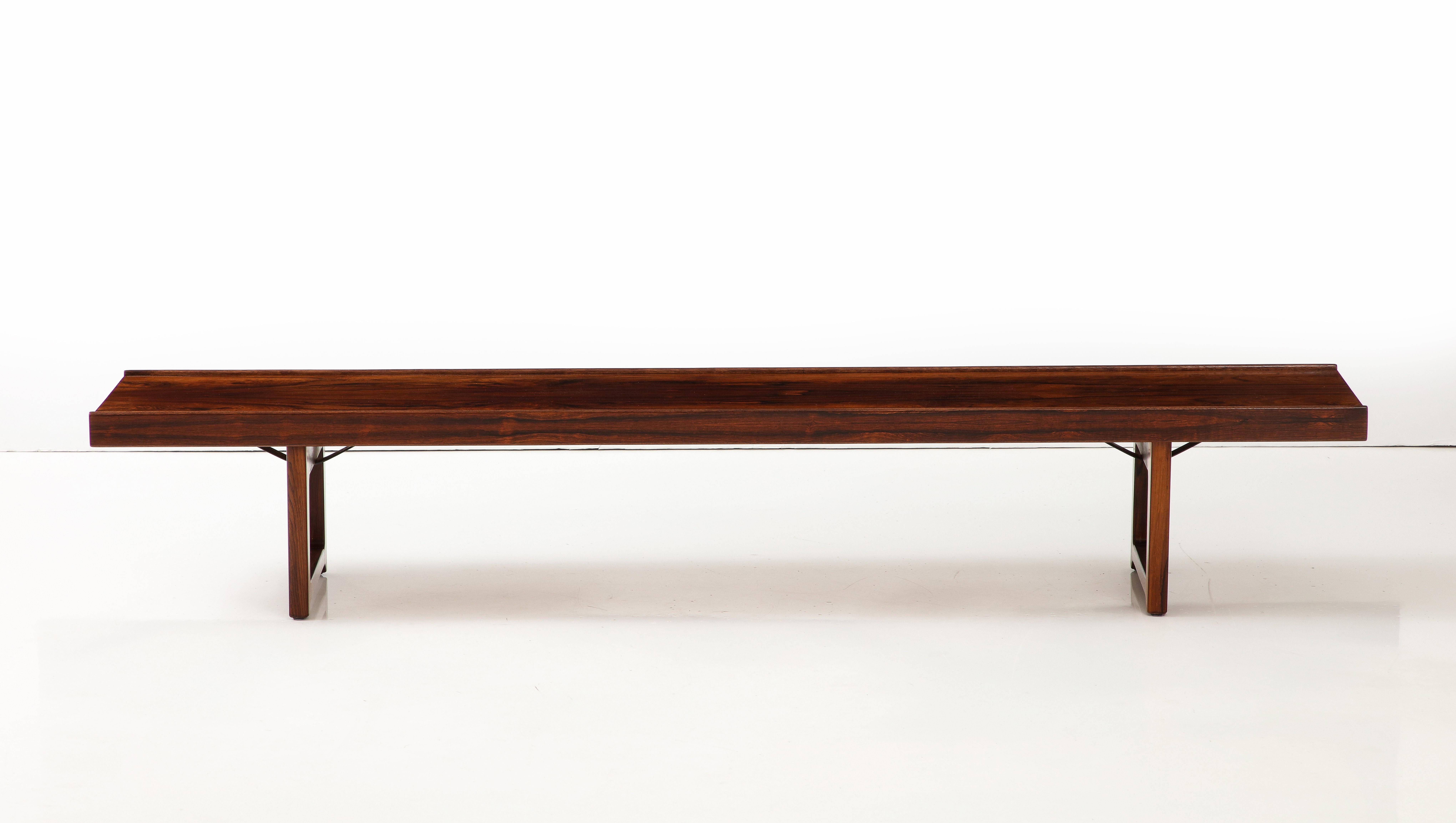 A Norwegian Krobo rosewood long bench or table, Designed by Torbjørn Afdal, Circa 1960s, Manufactured in Norway by Mellemstrands Trevareindustri. the rectangular top with raised outer molding on the sides. Beautiful rosewood grain which is