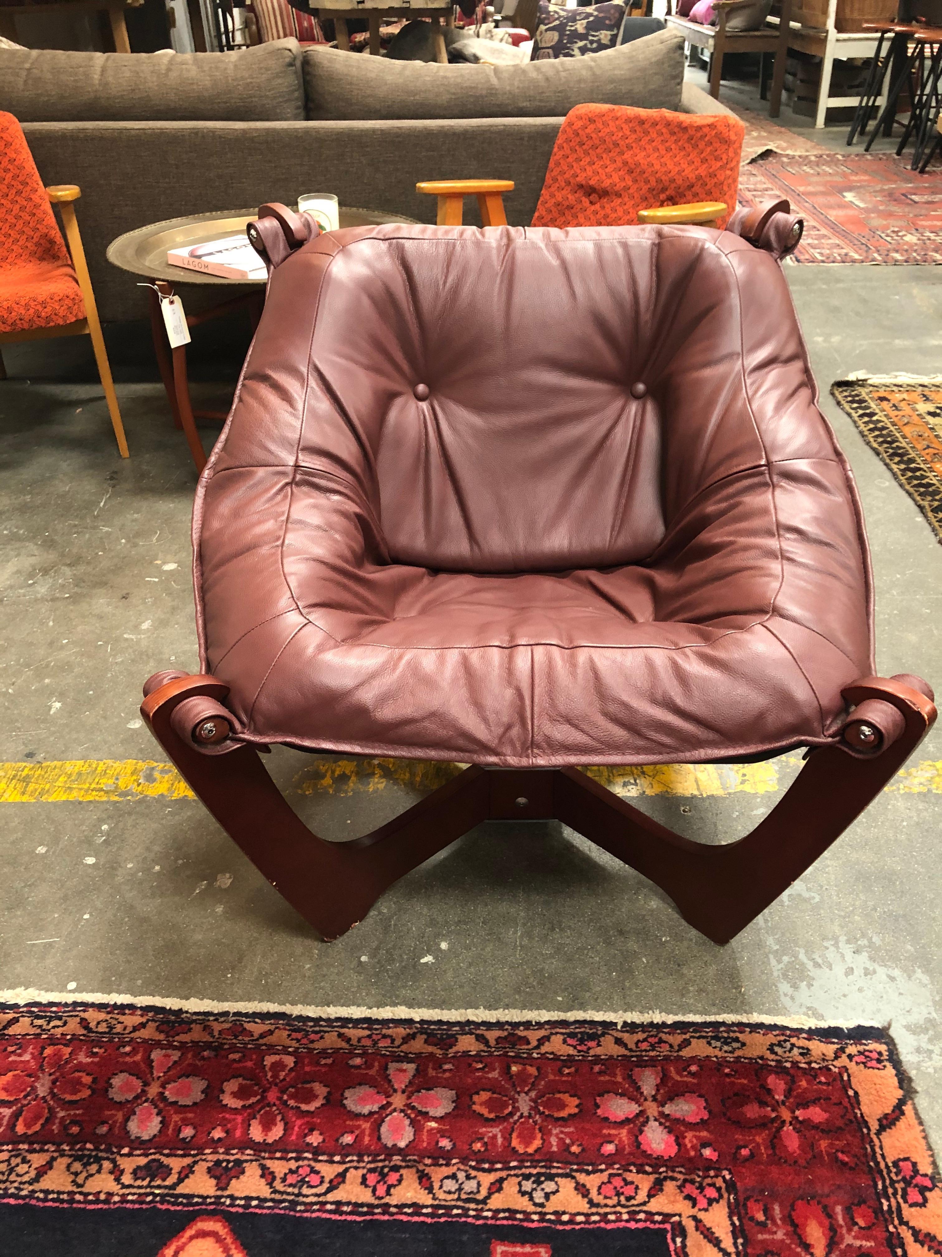 Leather lounge chair in burgundy color with a wooden base.
