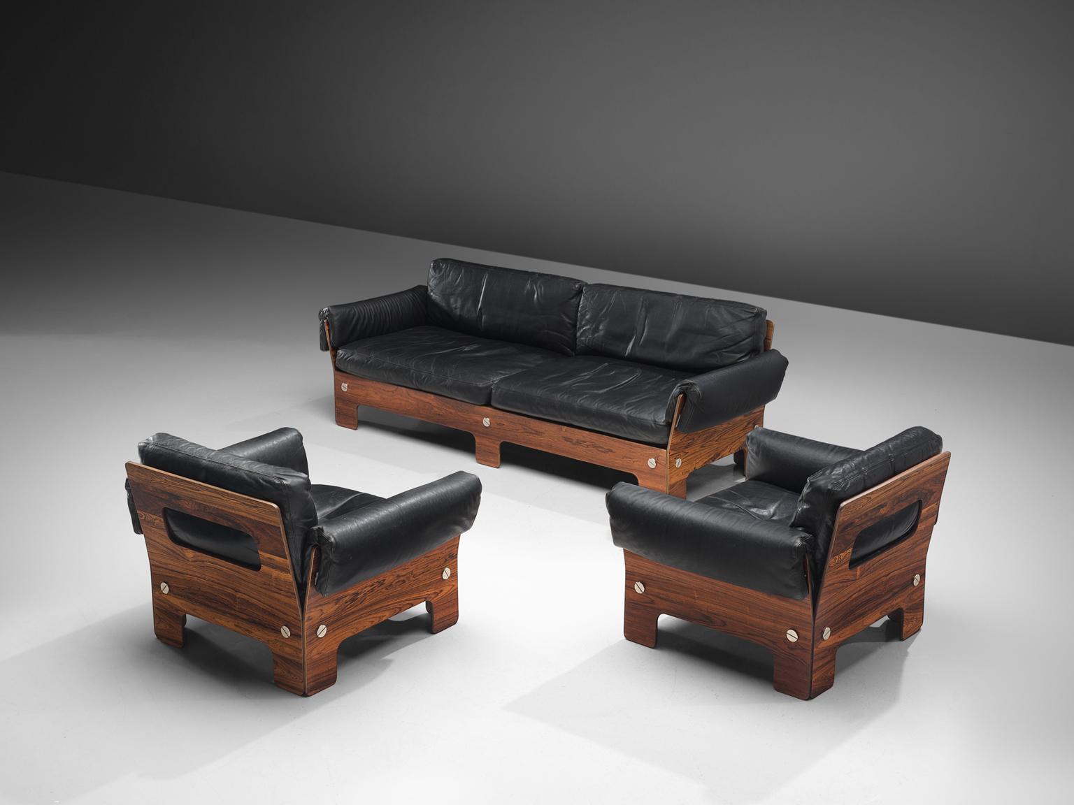 Sofa and chairs, rosewood and black leather, Norway, 1960s. 

This living room set which comprises of two lounge chairs and one sofa, has very comfortable elements. The boxy look of the set is due to the square and rectangular shape of the chairs,