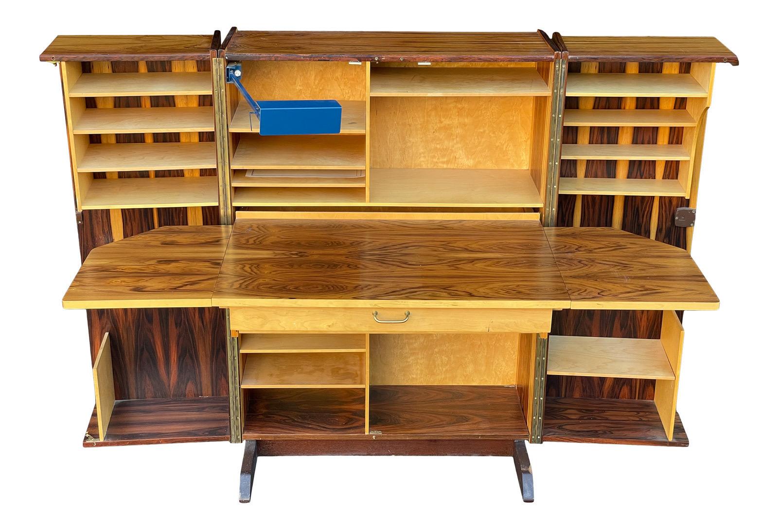 A vintage Norwegian hideaway desk, produced circa 1960s, in the Scandinavian Modern style; this versatile desk can compact into box, veneered in rosewood and expand into a full office with extensive shelving space, desk and foldable leaves, Overall