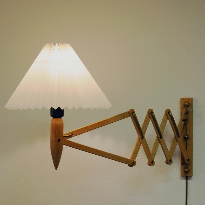 Wall-mounted scissor lamp in oakwood originally from Norway, 1960s. These lamps were very popular in Scandinavia during the 1960s. It stretched out position is about 60 cm and folds down to about 20 cm. It is also adjustable sideways. The lamps is