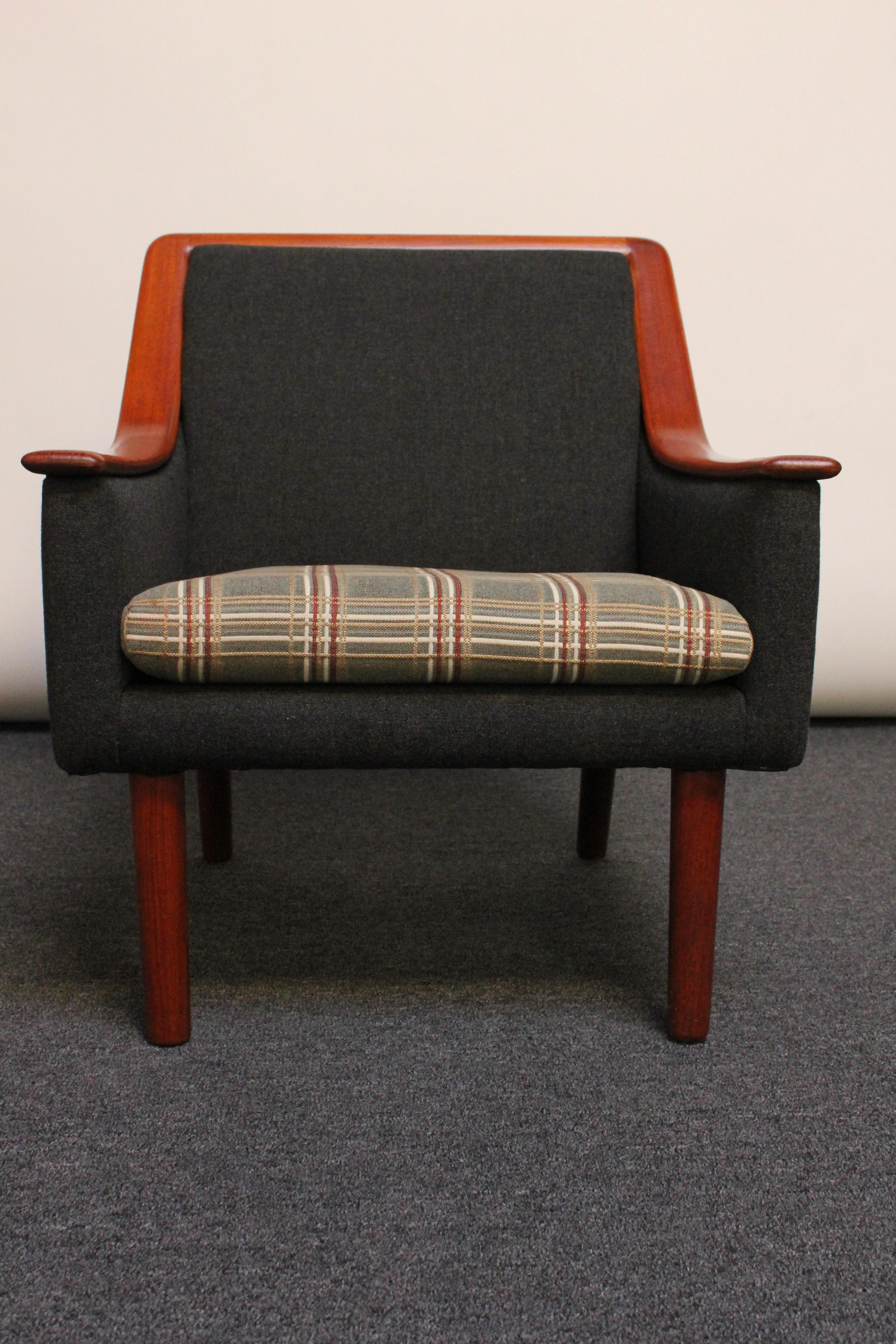 Mid-Century Modern arm chair with a continuous, exposed teak arm / back trim (Norway, ca. 1960s). Retains the original upholstery composed of a charcoal wool frame with a contrasting cushion in red, green, white, and oatmeal plaid. The foam and