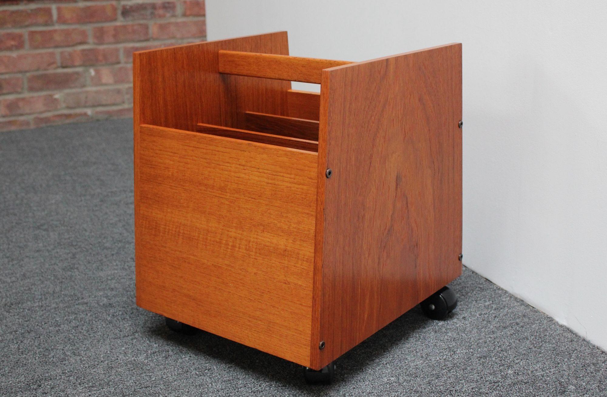 Mid-Century Norwegian Modern teak magazine rack designed in the 1960s by Rolf Hesland for Bruksbo.
Features three slots for books/magazines with a sculptural handle, all supported by four caster wheels for easy mobility.
Retains the 