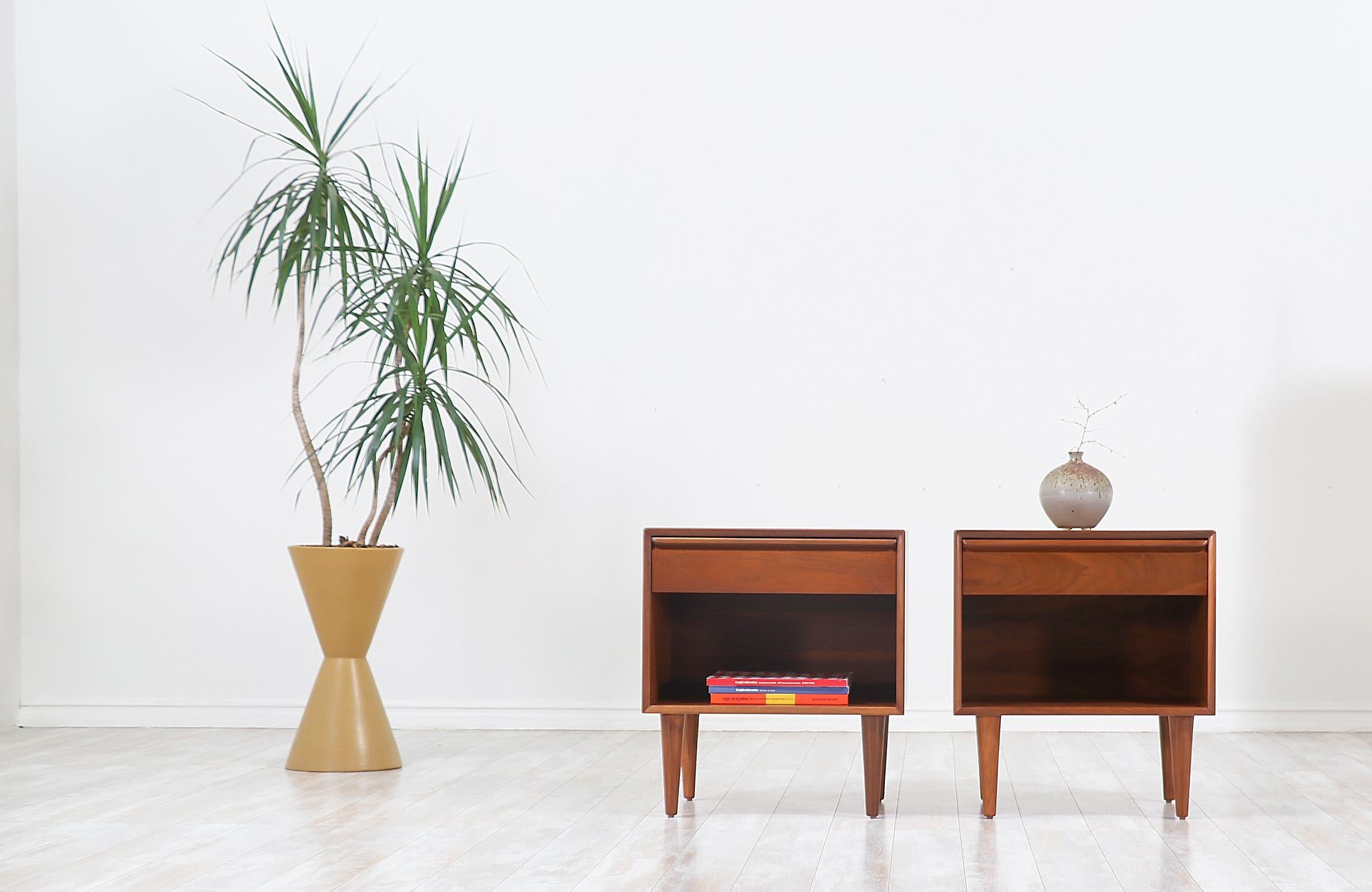 Pair of Scandinavian Modern nightstands designed and manufactured by Westnofa furniture in Norway, circa 1960s. This beautiful set of nightstands features a sturdy walnut wood case with four Classic taper legs for a clean and Minimalist aesthetic.