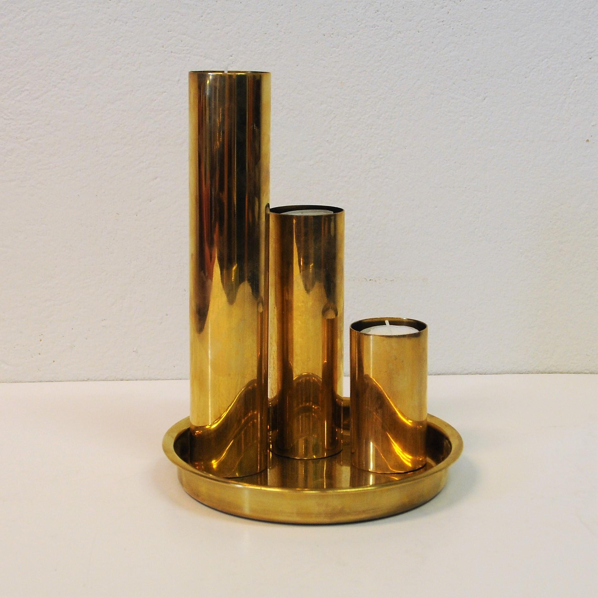 Three attractive and stylish Norwegian brass cylindrical candlesticks or just ornaments/display pieces on a brass-plate. All have same diameter but are in different heights of 25 cm, 16 cm and 9 cm. 5 cm in diameter. The brass plate (19 cm D) has a