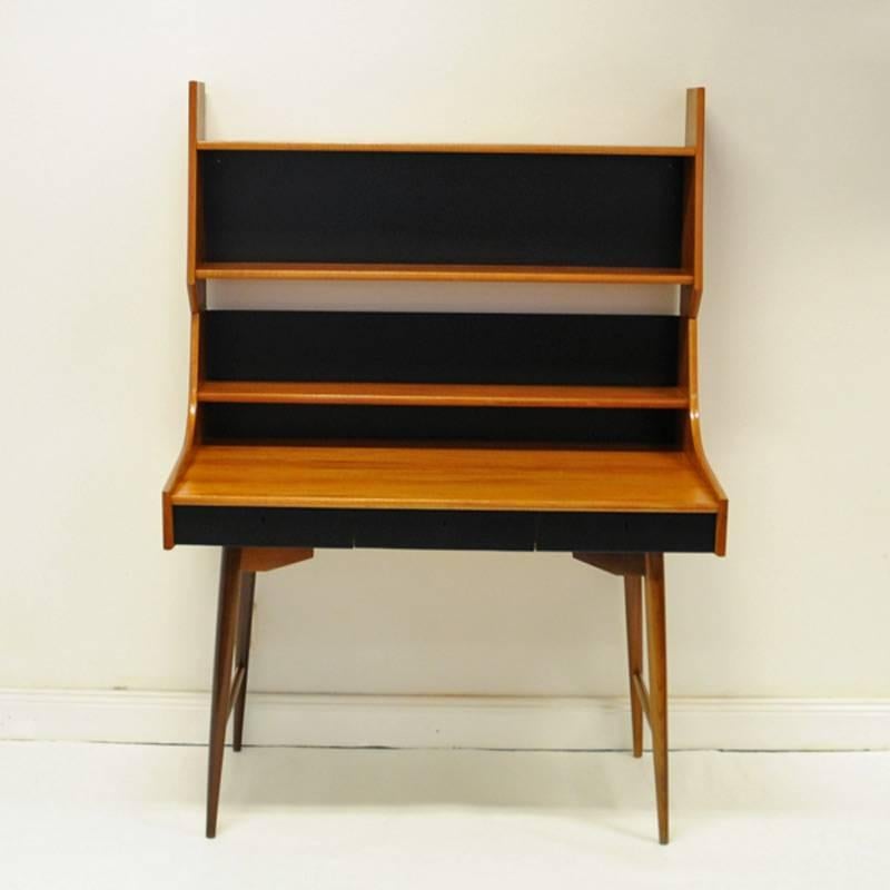 The Norwegian design classic Ola desk (Ola pulten) by John Texmon. Late 1950s. Produced by Blindheim Møbelfabrikk. In teak and partial back in black melamine. With an extra shelf to add over the desk. Beautiful design and nice patina. Measures: