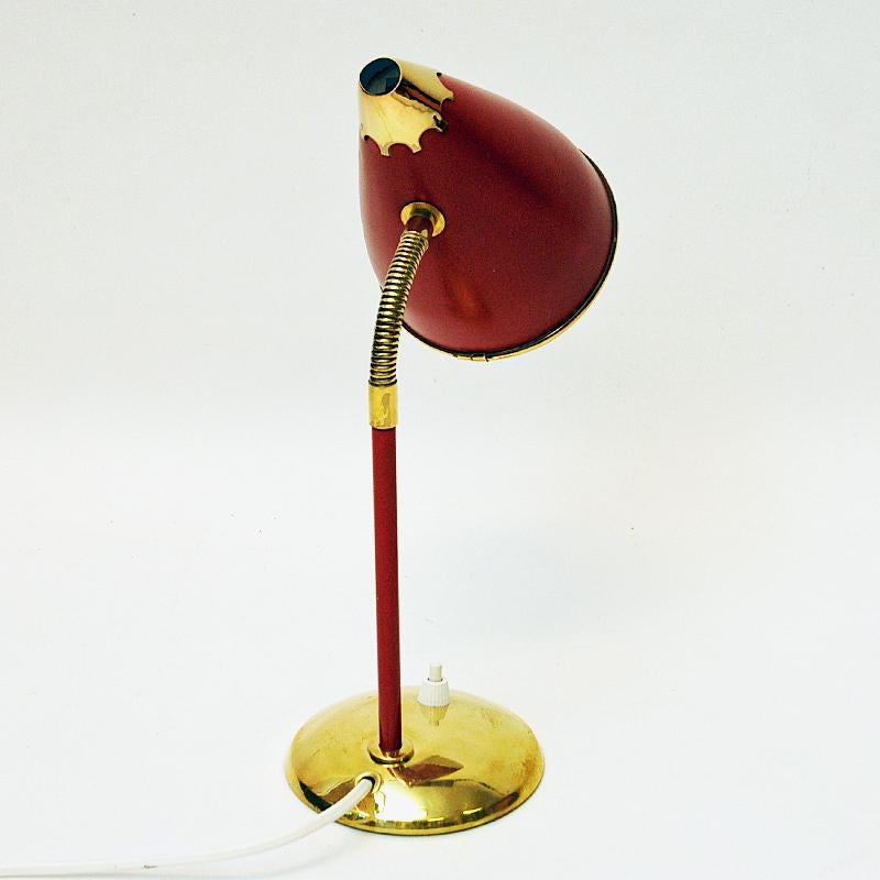 Classic design metal and brass desk lamp with an adjustable goose neck probably by the company T. Røste & Co Norway 1950s. Red laquered lampshade with a shape as a cone. White inside and red stom. Light switch located on the brass base. Small mark