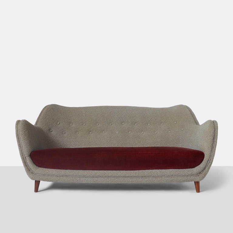 Sofa on walnut legs with red velvet bench seat and 1960s textured upholstery.