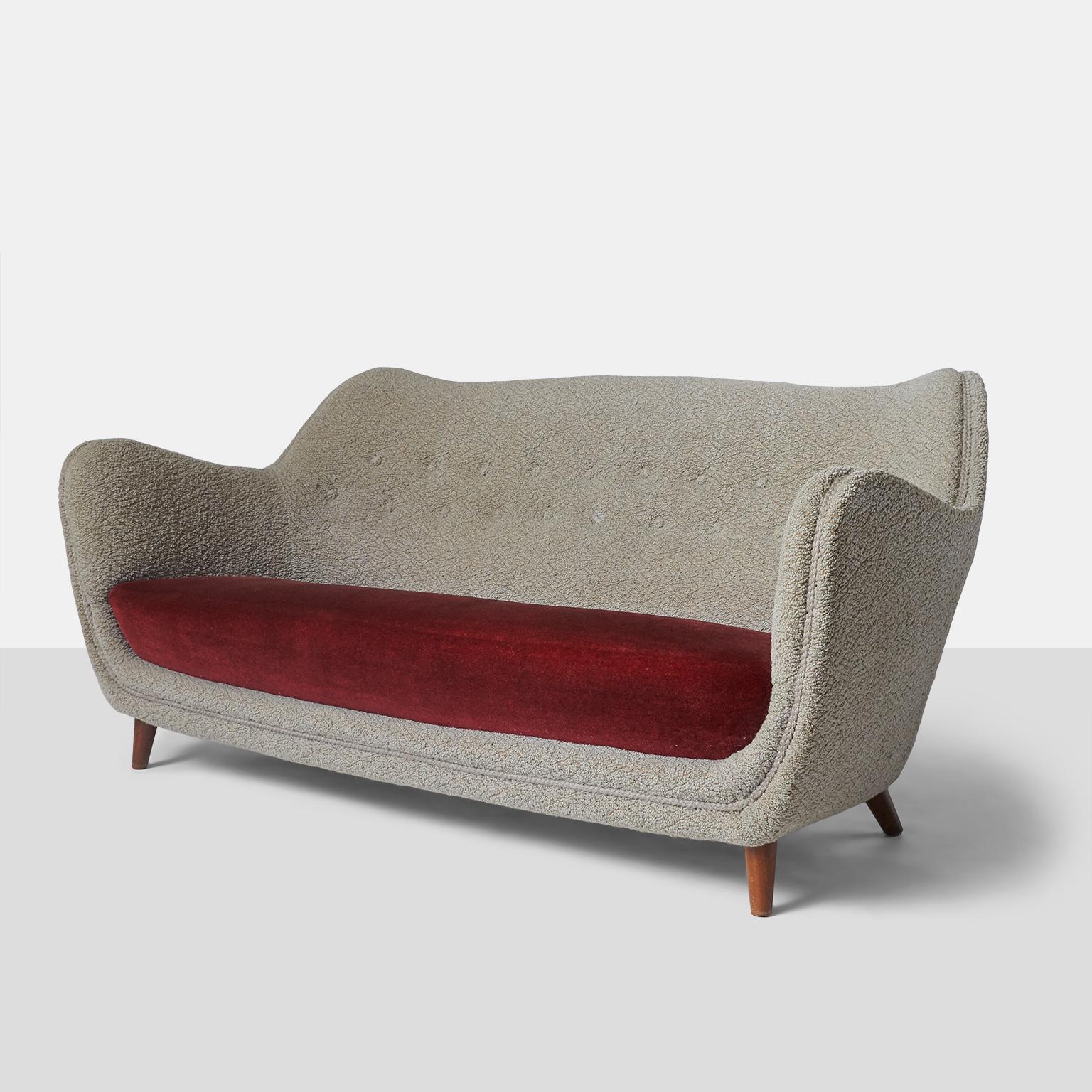 Sofa on walnut legs with red velvet bench seat and 1960s textured upholstery.