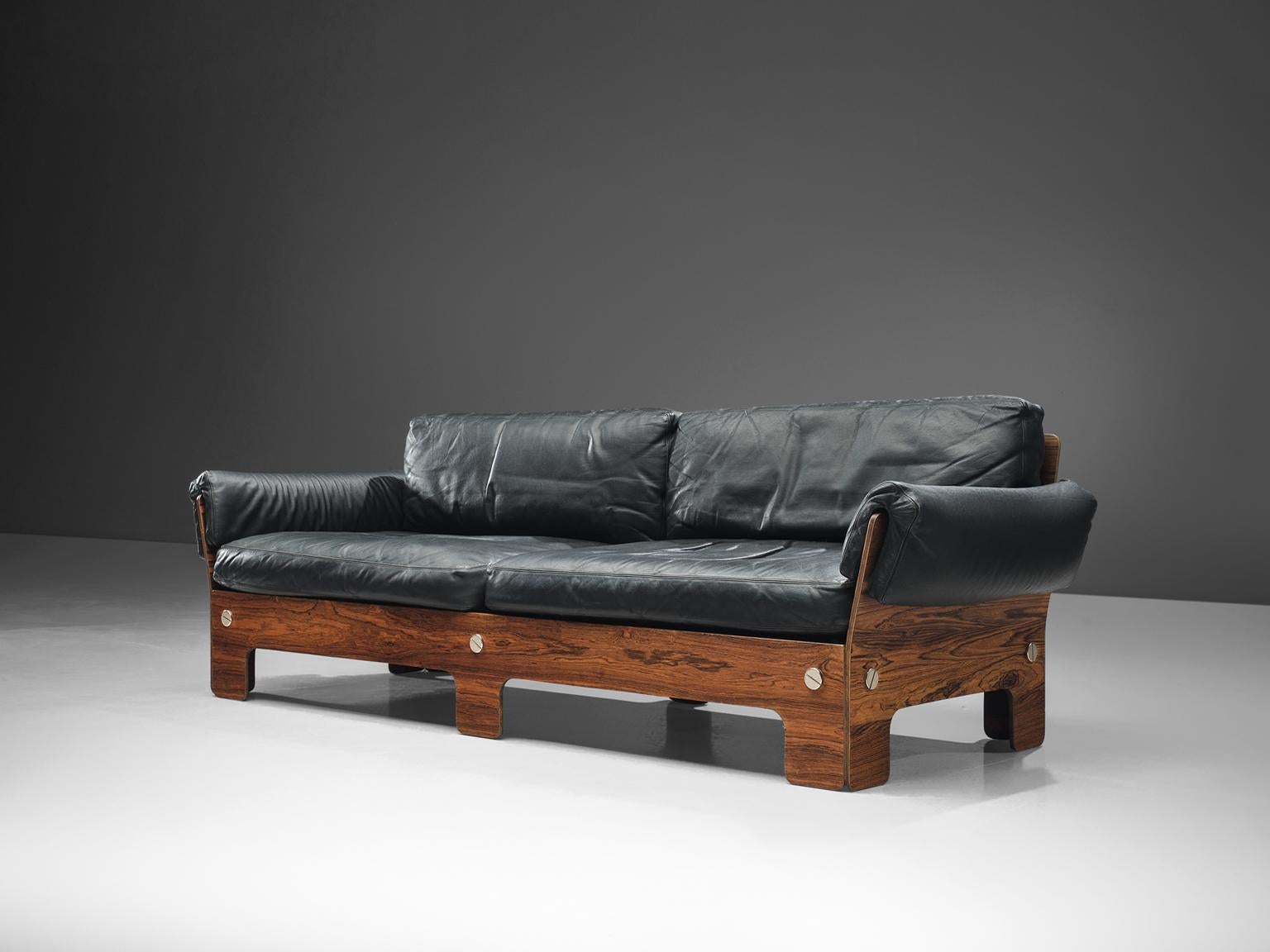 Sofa, rosewood and black leather, Norway, 1960s

This sofa presents very comfortable elements. The boxy look of the sofa is due to it's square and rectangular shape, which creates an potent look.
The cushions are wrapped around the rosewood