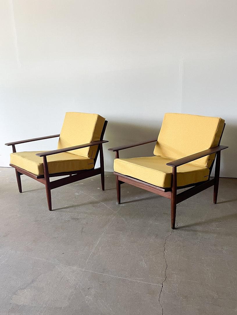 This is a fantastic pair of solid teak paddle arm lounge chairs made in Norway in the 1960s. The Scandinavian mid-century modern lounge chairs are exceptionally well made with sleek, sculptural arms and beautiful wood grain. New yellow cushions for