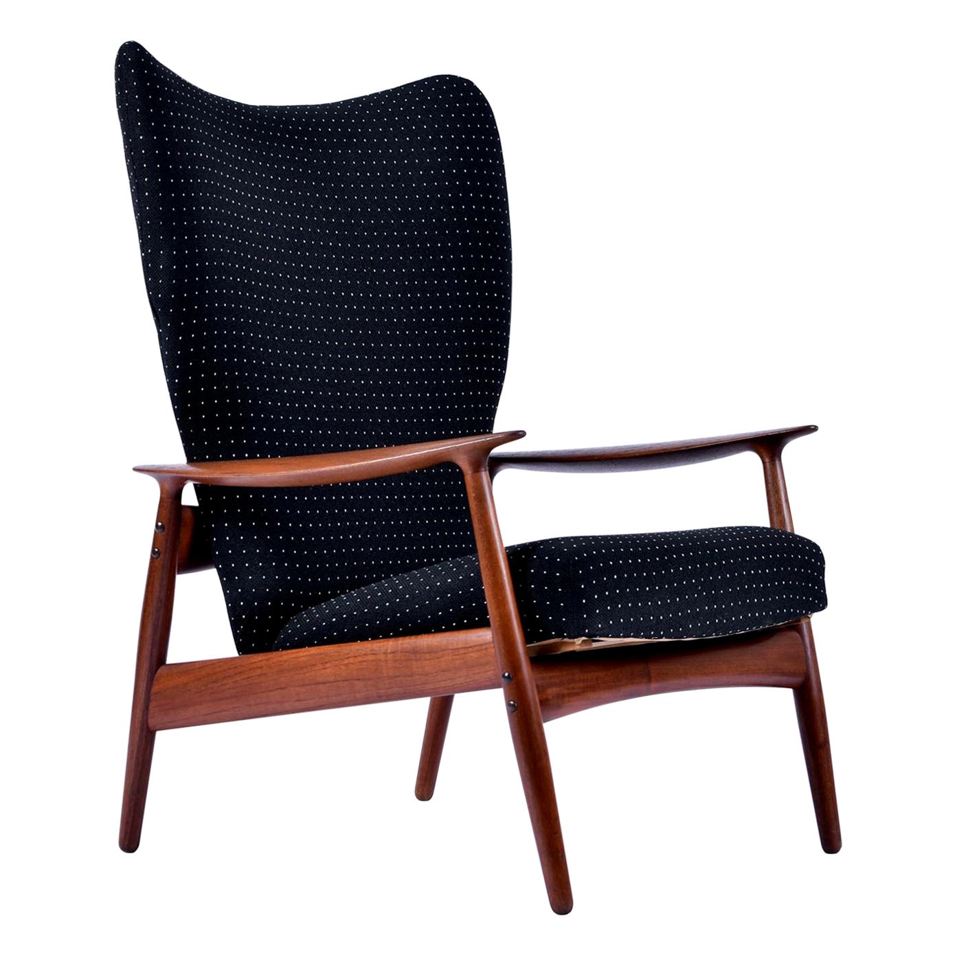 Stunning wingback lounge chair designed by K. Rasmussen for Peter Wessel. The teak has aged to a beautiful redish-amber that perfectly compliments the newer (not new) black tweed fabric. The lounge chair easily adjusts into a reclined position that