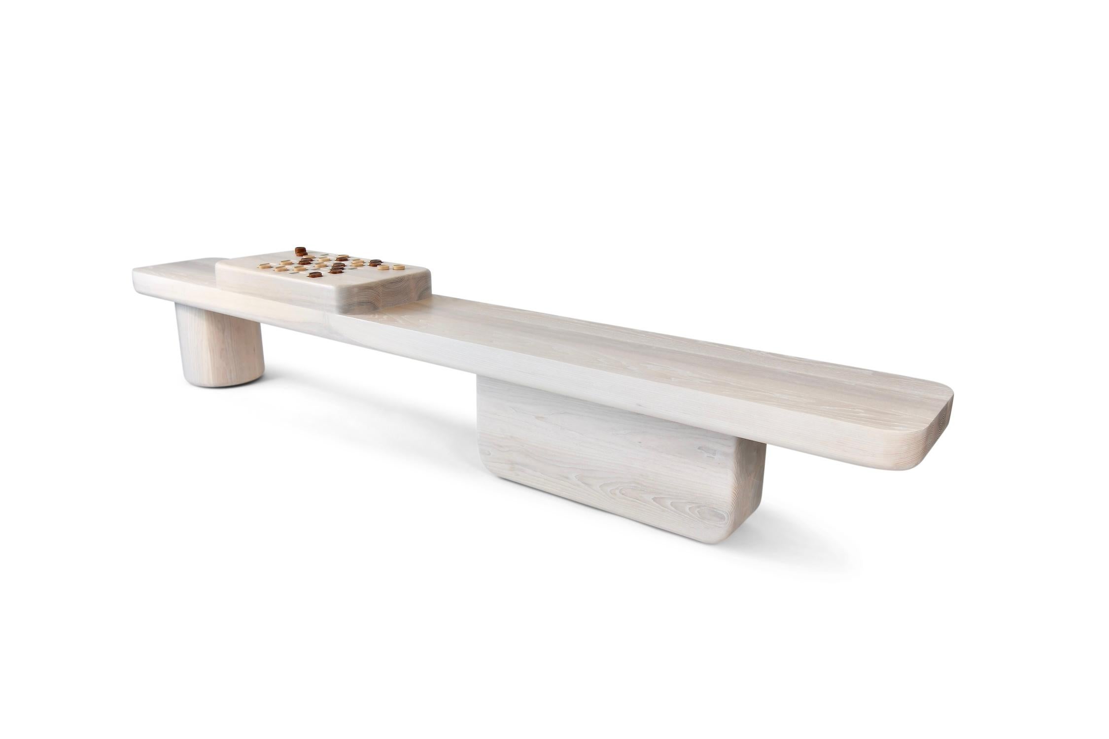 The Nostromo Bench is a monolithic solid wood slab top anchored by a large sculpted rectangular base and round column. This statement piece features an integrated chess/ checkerboard that harkens back to an earlier time. 

The game table engages the