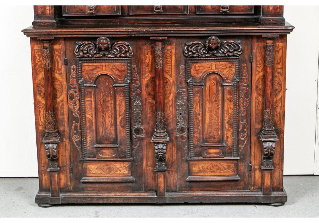 Un gran e impresionante armario europeo del siglo XVII. Fabricado en dos partes, ambas con elaborada decoración tallada y paneles y detalles burilados. El mueble superior tiene una pesada encimera sobre dentil y frisos de marquetería burilada. La