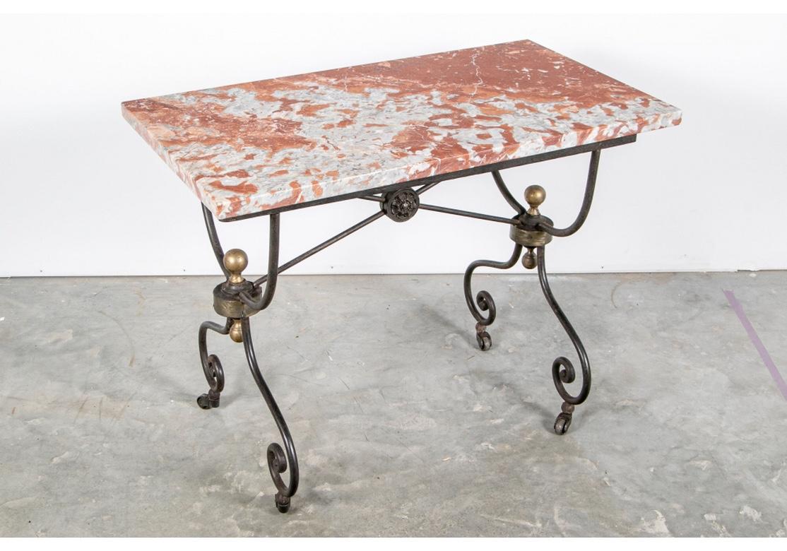 Fine red and gray marble topped iron table with U-shaped supports, brass ball topped joins for the scrolled legs on casters. With an X-stretcher with rosette center. The table is in an adaptable smaller size while having all of the style and