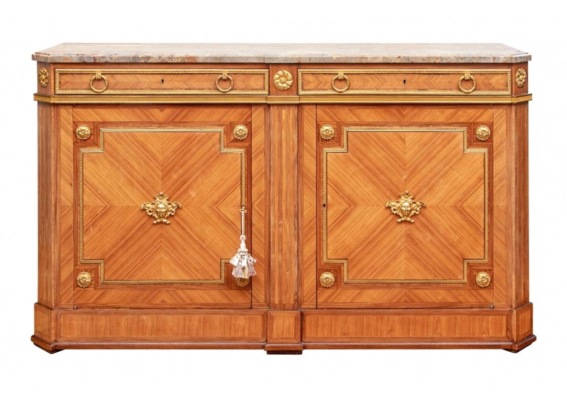 Extraordinary pair of stone top cabinets with bronze mounts. Elegant and fine construction in pale walnut parquetry for the frieze drawers and door fronts. Gorgeous variegated marble top with shaped corners. The case with canted fluted corners and