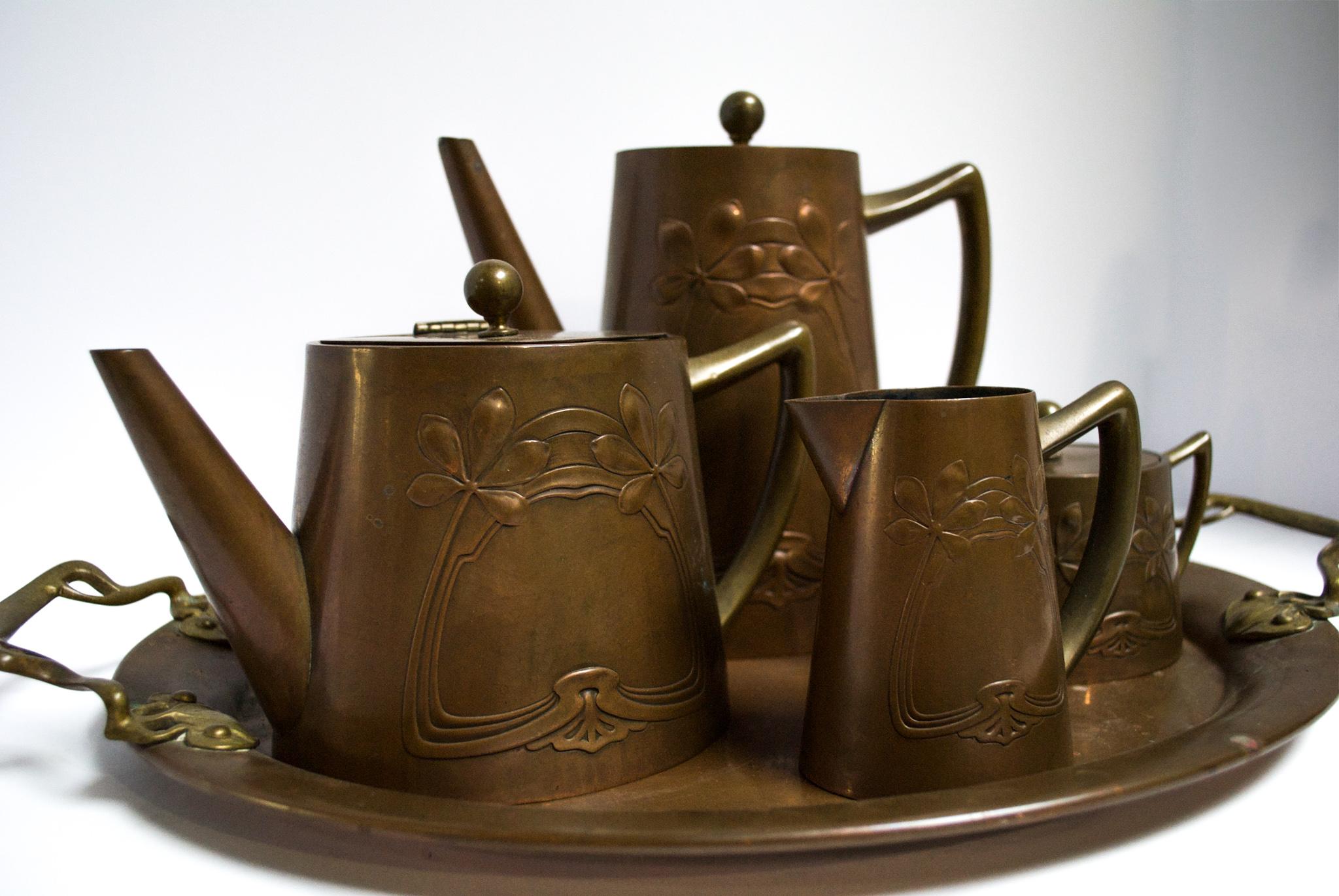 fleurdetroit presents for your consideration a wondeeful tea service from the Arts and Crafts period. Dazzle guests with a one of a kind find like this early 20th century coffee/tea set. Made of copper, this set features an art nouveau design on