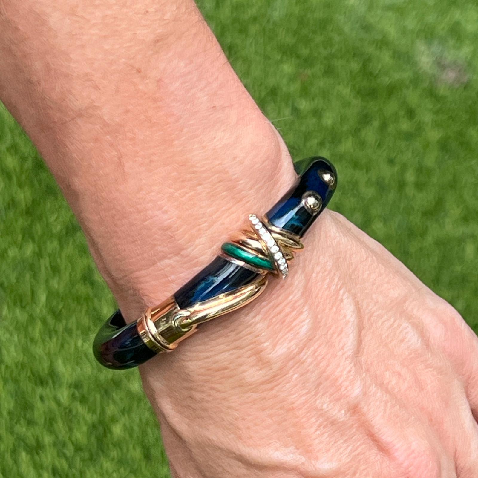 Italian designer La Nouvelle Bague diamond and enamel hinged bangle fashioned in 18 karat yellow gold. The bangle features 13 round brilliant cut diamonds in a row weighing approximately .26 carat total weight. The navy blue and green enamel