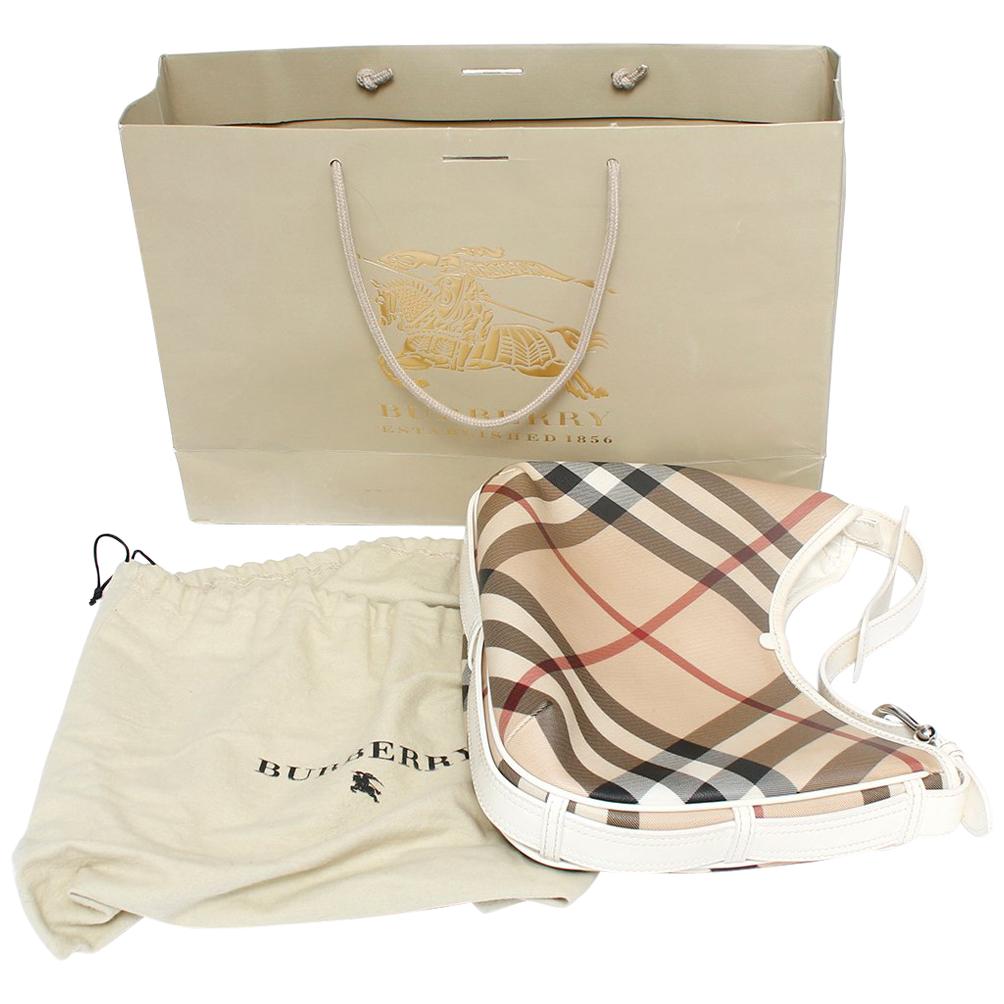 This chic hobo is crafted of classic Burberry Nova check canvas. The bag features a white leather shoulder strap and bag trim with polished silver hardware. The top is open to a beige fabric interior. Pre-owned in excellent near to Mint Condition.