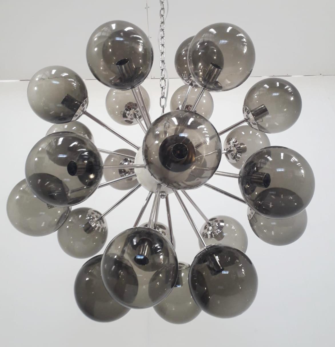 Lampadario sputnik italiano con globi in vetro di Murano fumé montati su una struttura in nichel lucido con centro e baldacchino smaltati di bianco / disegnato da Fabio Bergomi per Fabio Ltd / Made in Italy 
24 luci / tipo E12 o E14 / max 40W