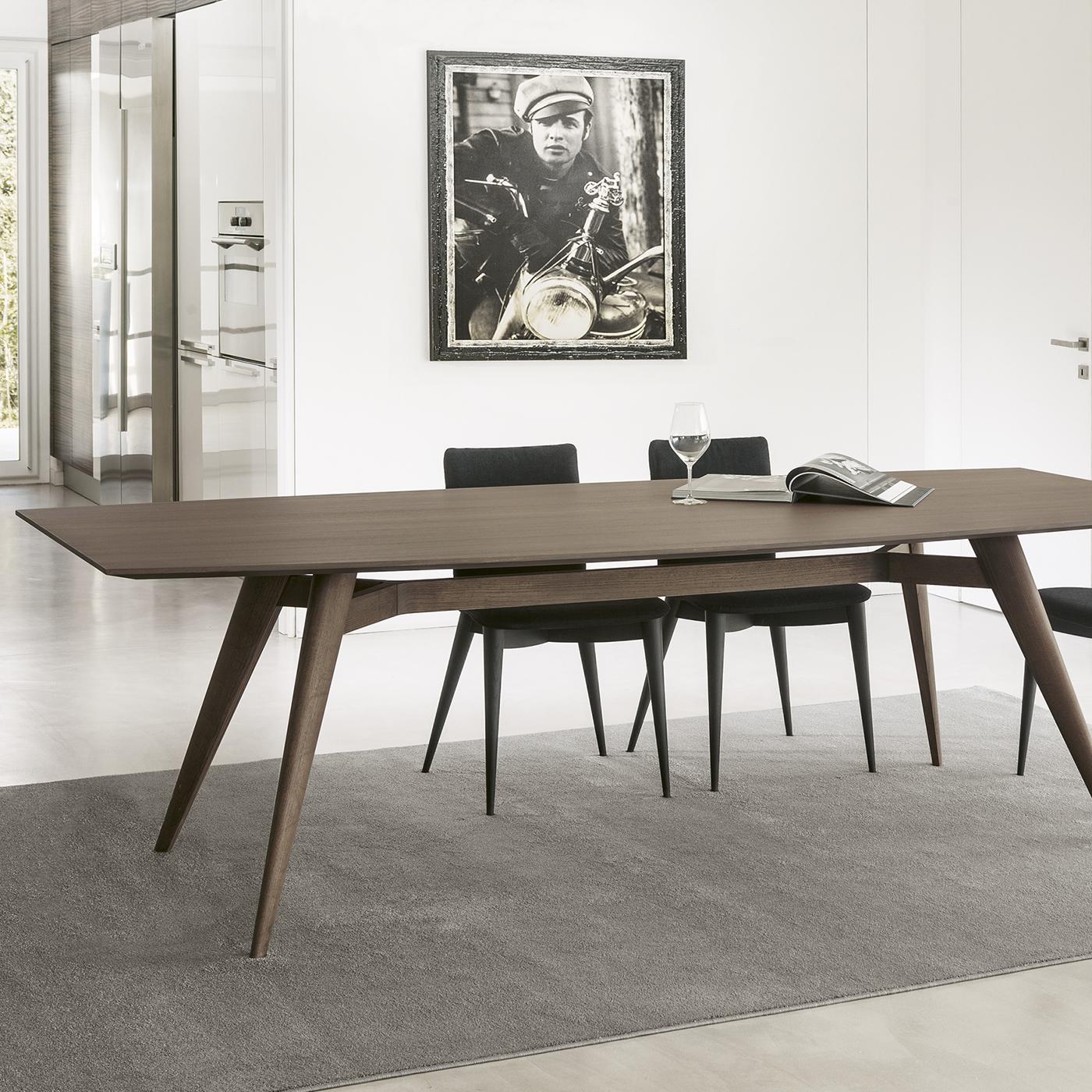 An ode to midcentury clean and charming design, this dining table was designed by architect Fabio Rebosio and is crafted of solid ash. The distinctive slated legs connect just below a wooden top. The finish of the wood can be in natural ash,