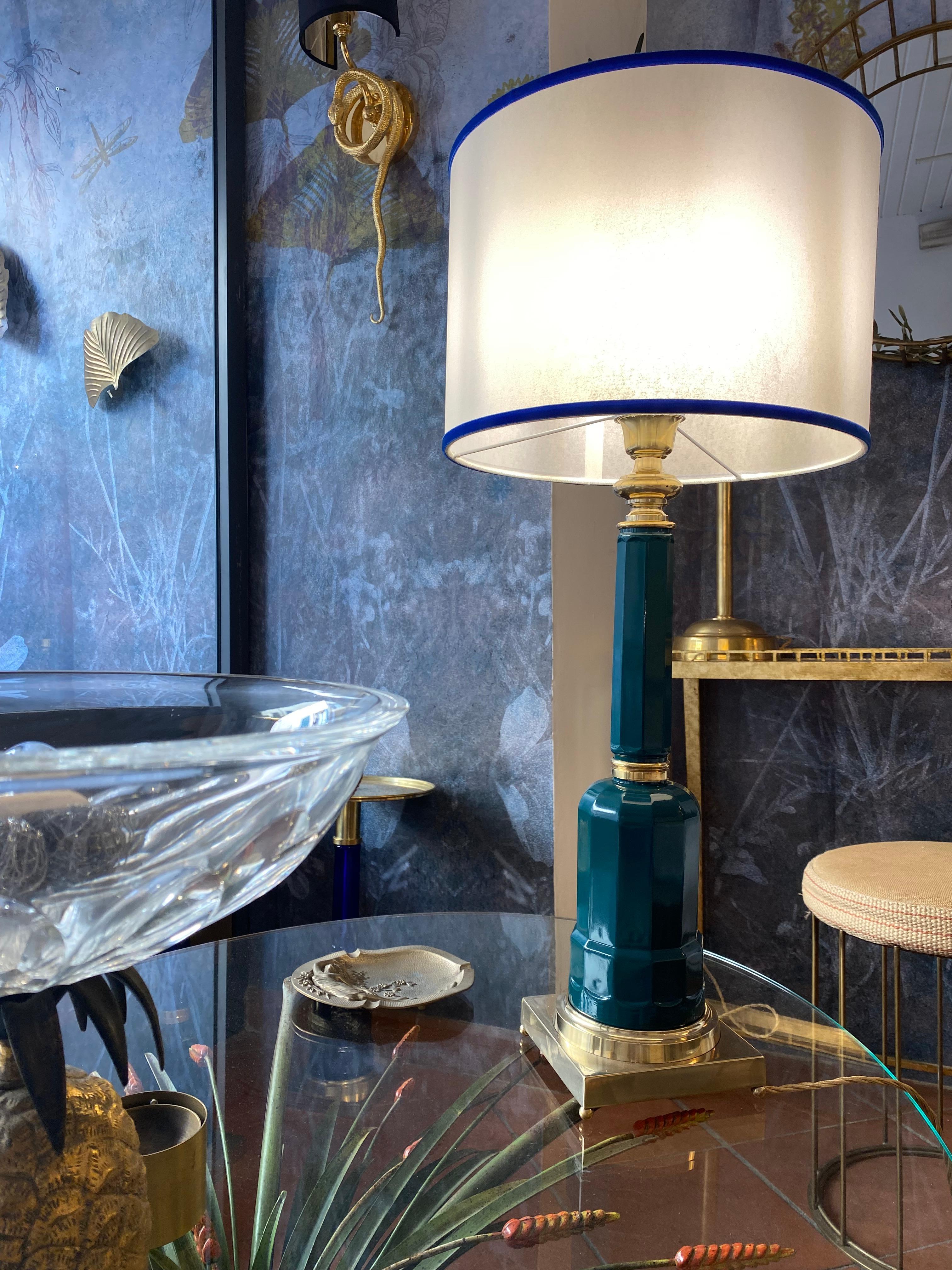 The Jacaranda table lamp is made of blown glass with the base and details in brass, natural finish, and fabric lampshade. The glass structure is obtained with the artisan technique of glass blowing inside a mold, usually of wood or carved metal, in