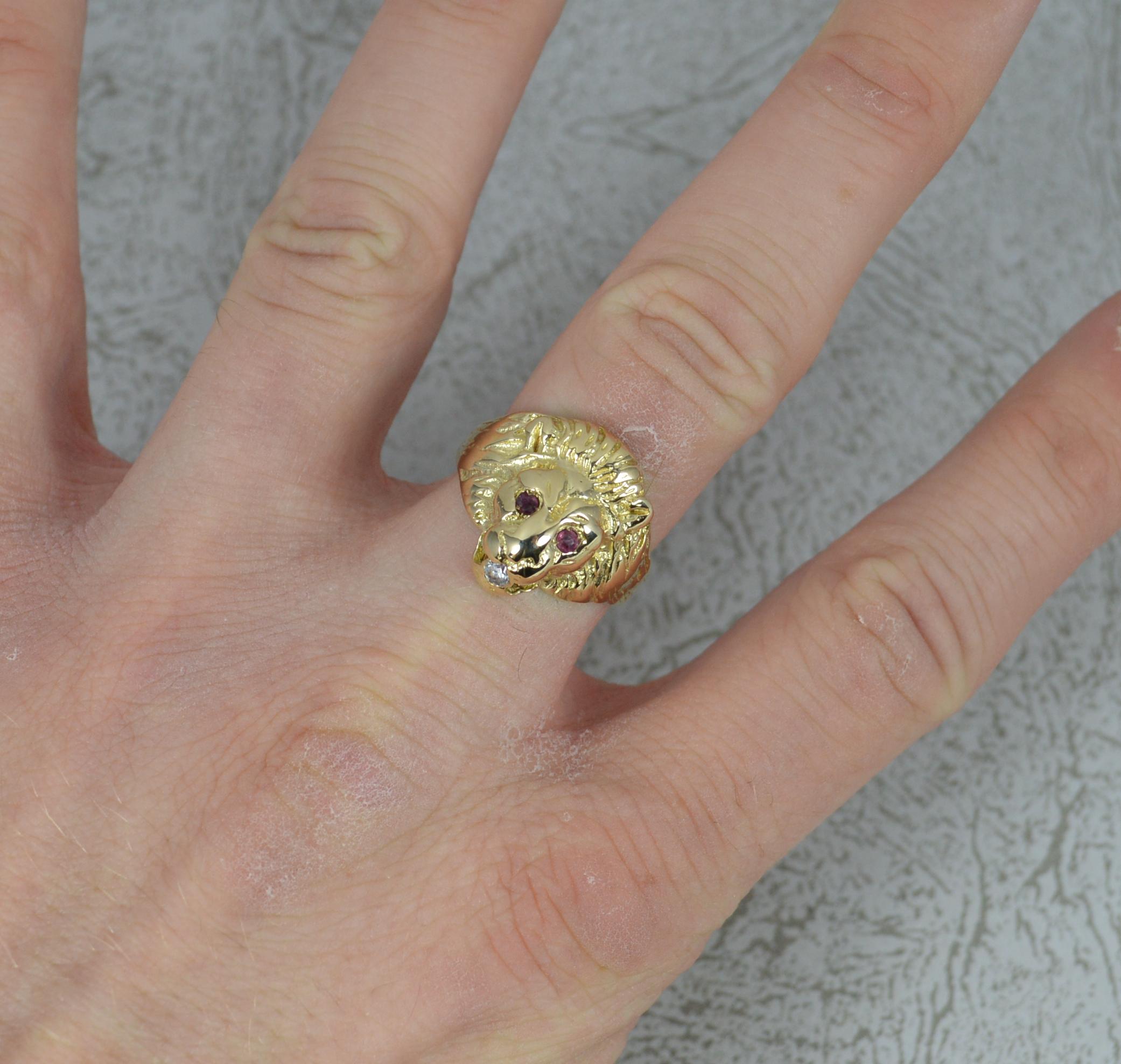 A fantastic realistically designed signet ring. Solid 9 carat yellow gold band. Set with a ruby for each eye and white paste in mouth. 13.6mm x 16.9mm lion head approx.

Condition ; Excellent. Well set stones, light wear to white stone. Crisp design
